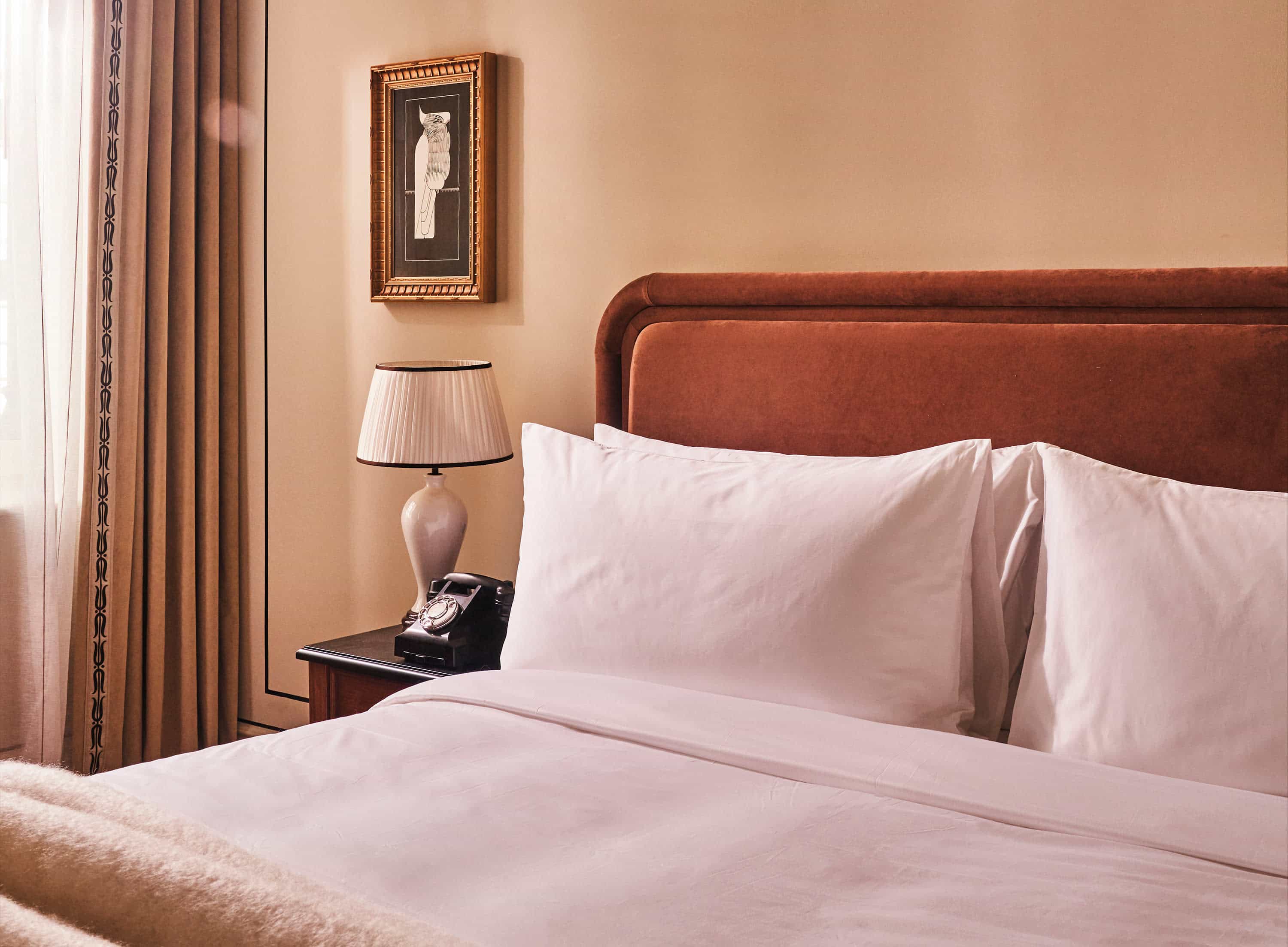 a luxe hotel room bed with a suede brown headboard