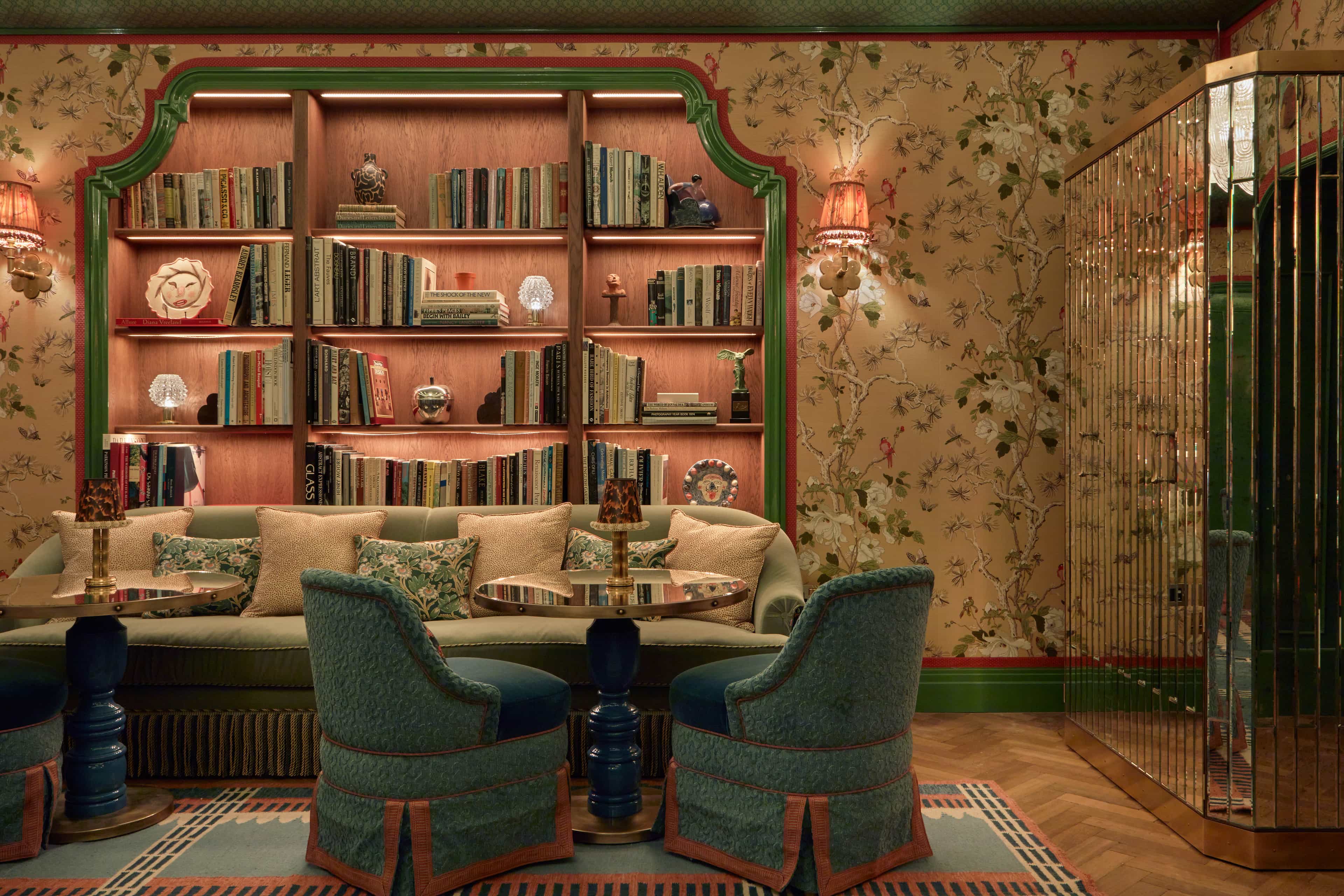a handsome library with patterned wallpaper and plush furniture