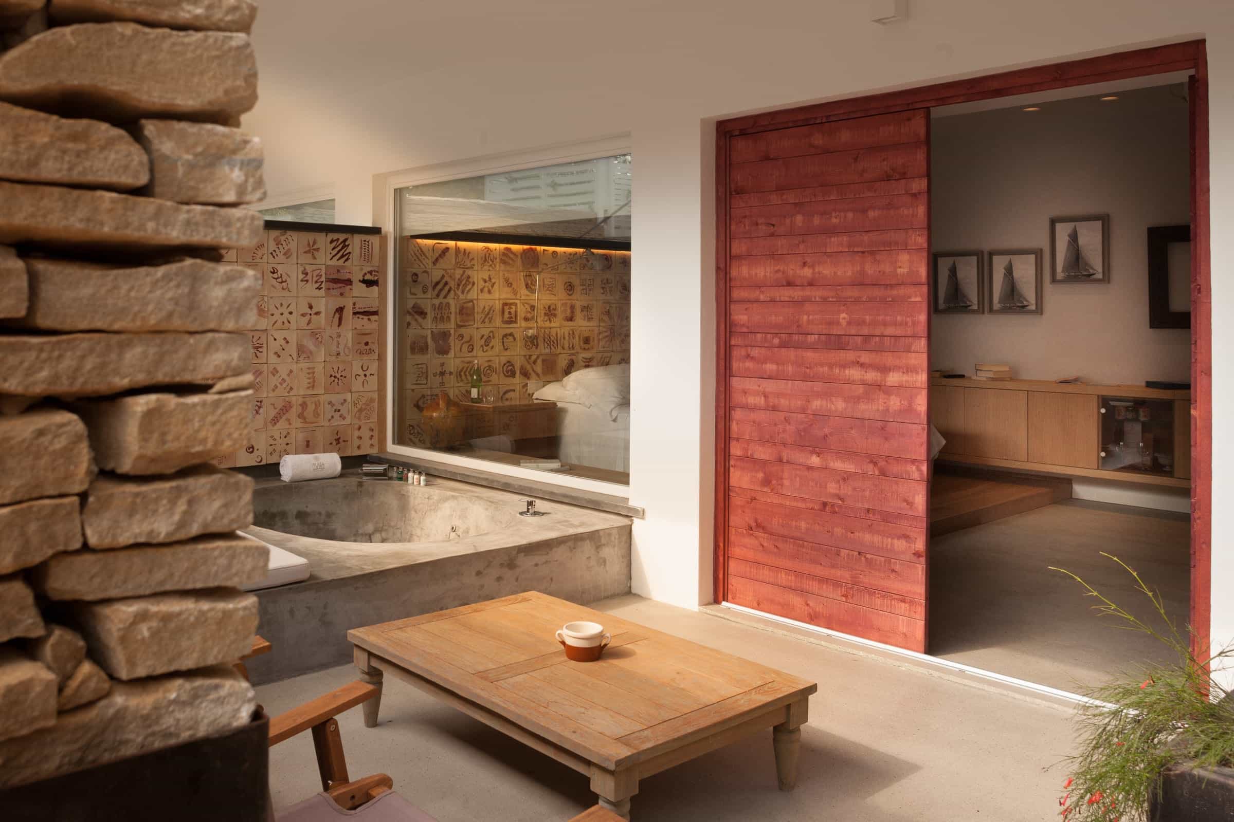 Hotel with terrace in wood, stone and natural tones, a low coffee table and stone plunge pool