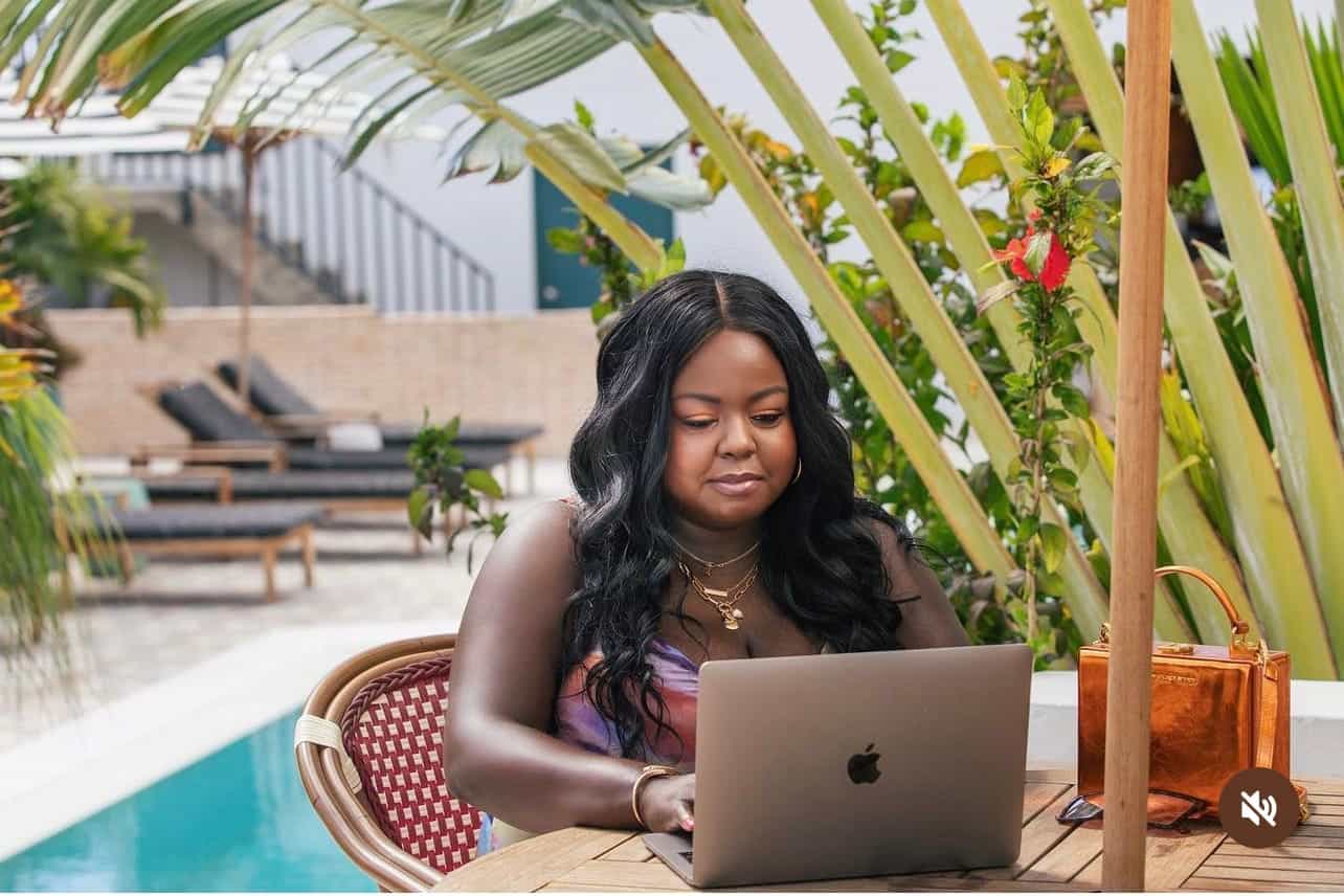 woman sitting poolside at a table working on a computer