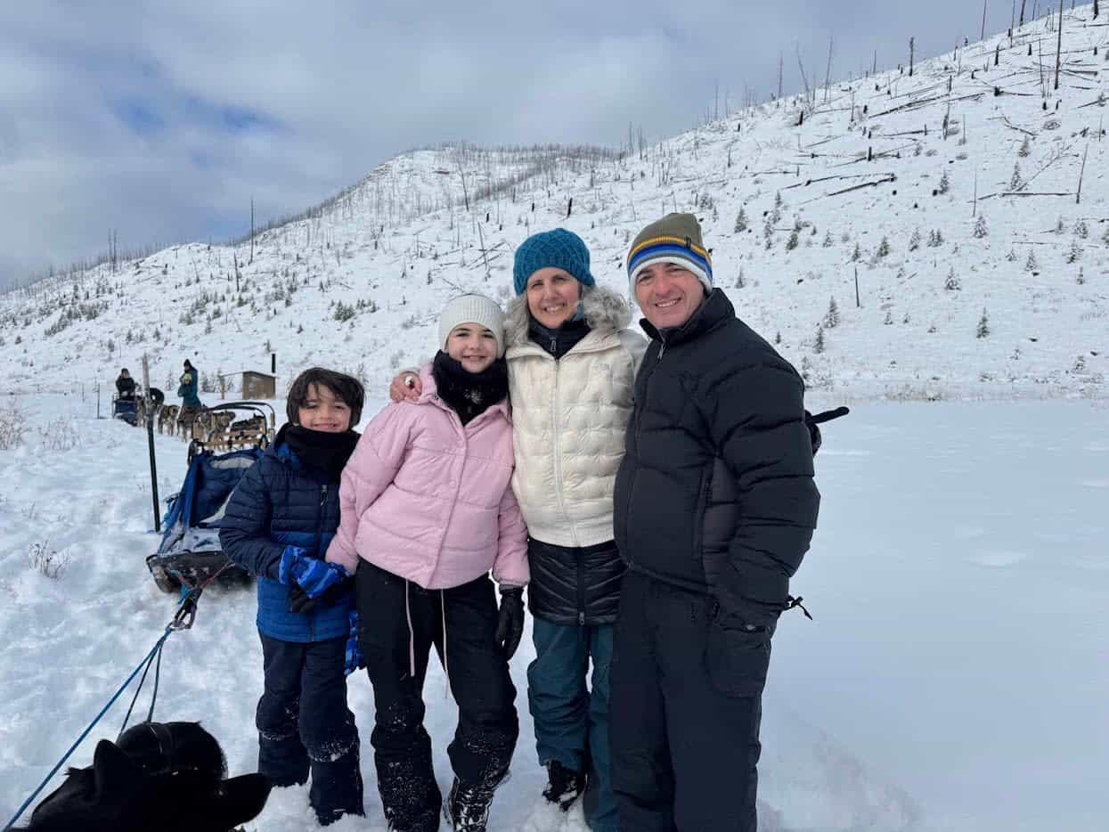 a woman and her family in winter clothing near a dog-sledding path