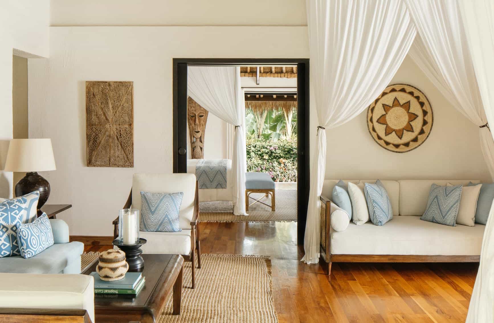 An elegant living room of a hotel villa with natural tones, wooden floor and tribal artwork.