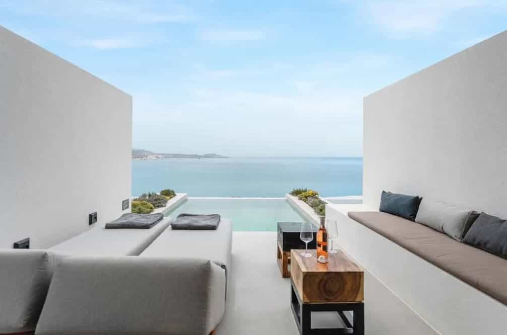 A sleek all-white hotel terrace with a plunge pool facing the ocean