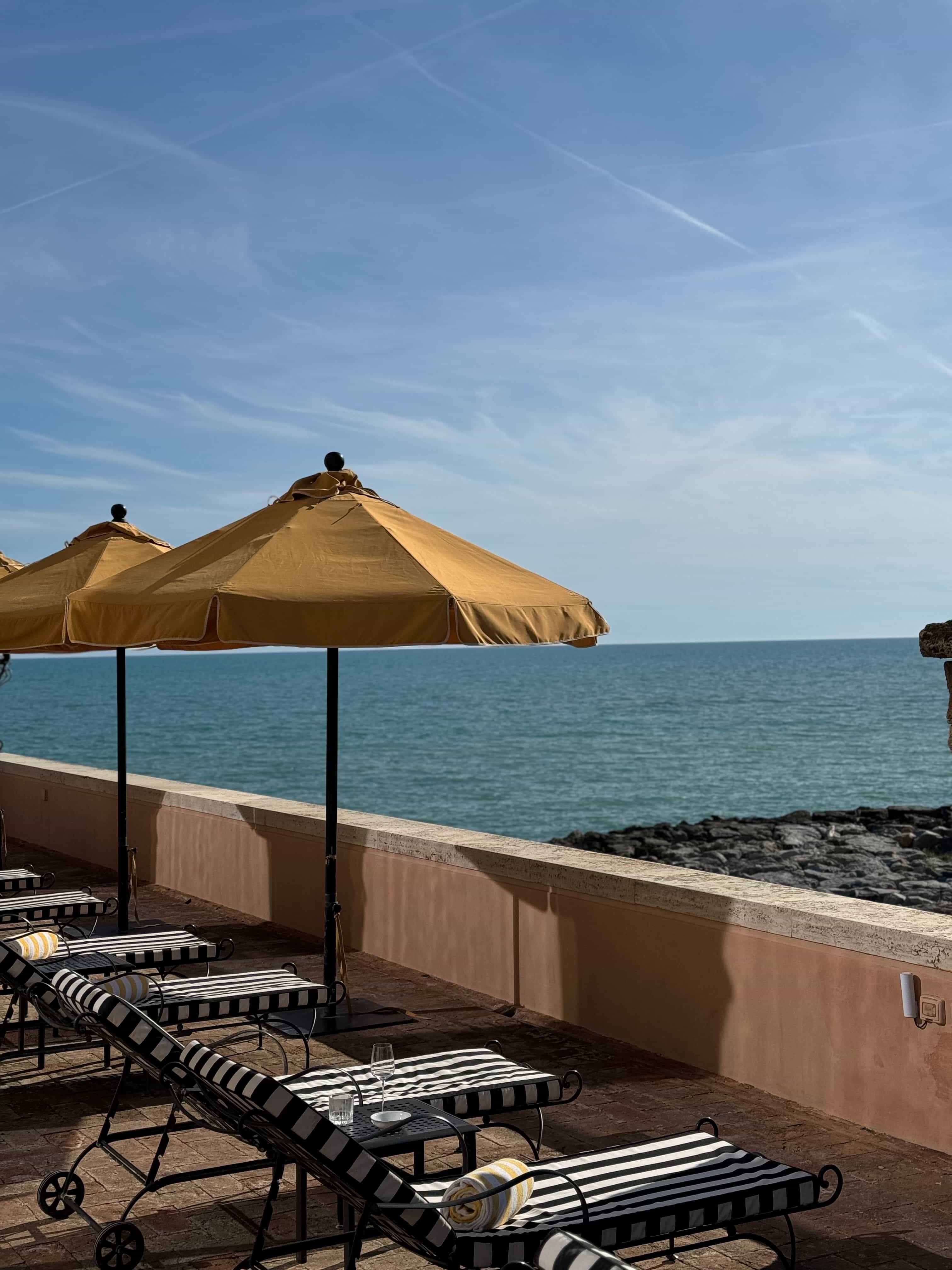 View of lounge chairs and yellow umbrellas looking out over the sea on a sunny day