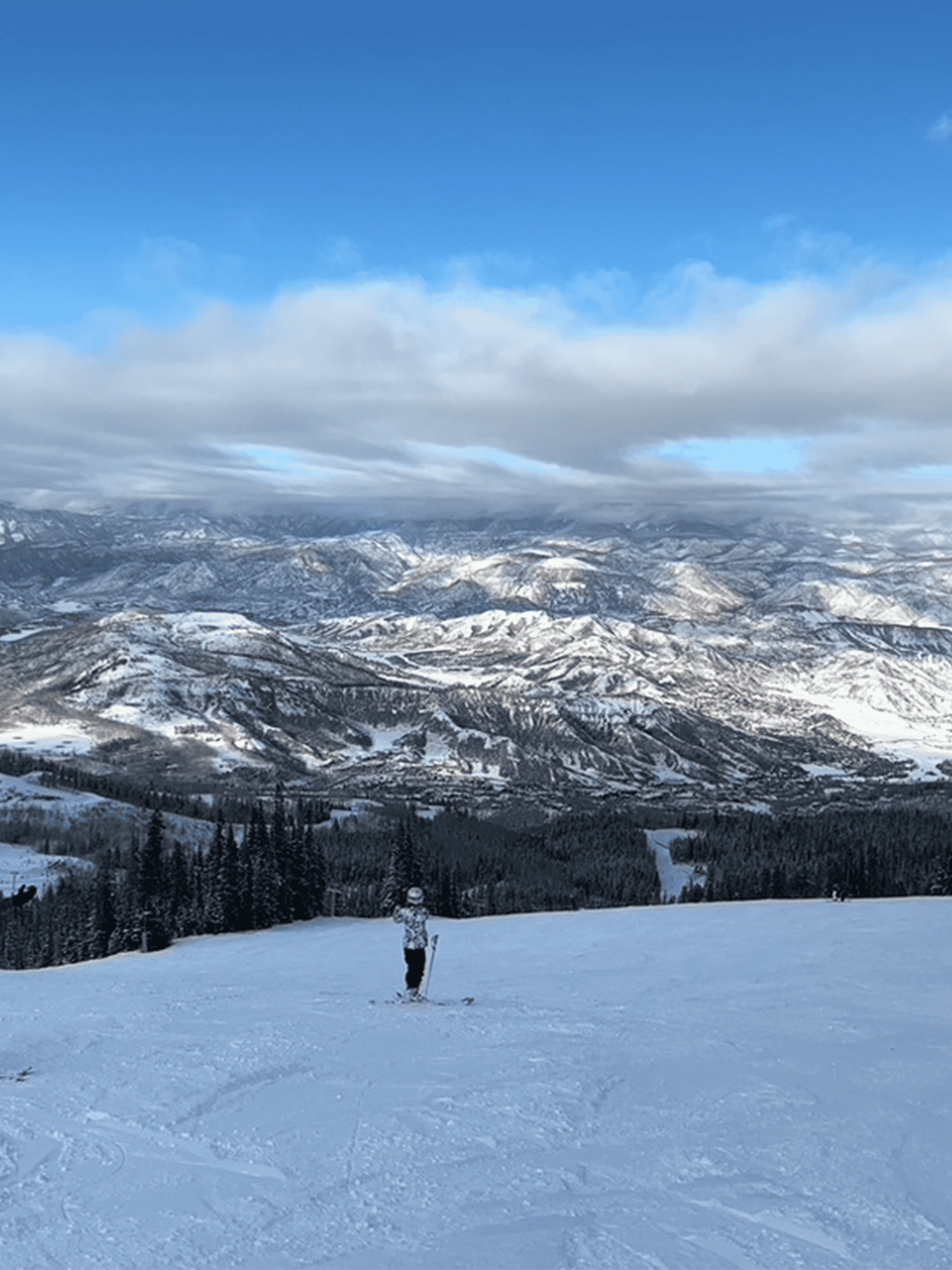 View of a person skiing on an empty slope with mountains visible in the distance