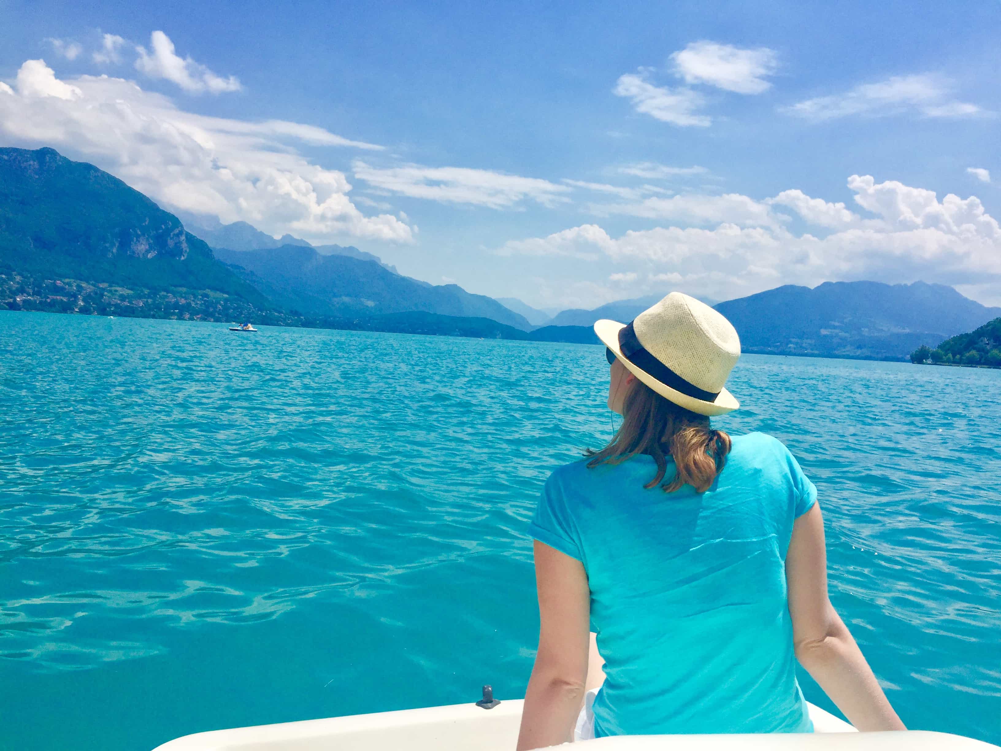 Advisor sitting on a boat, floating on blue water, and looking at mountain peaks in the distance.