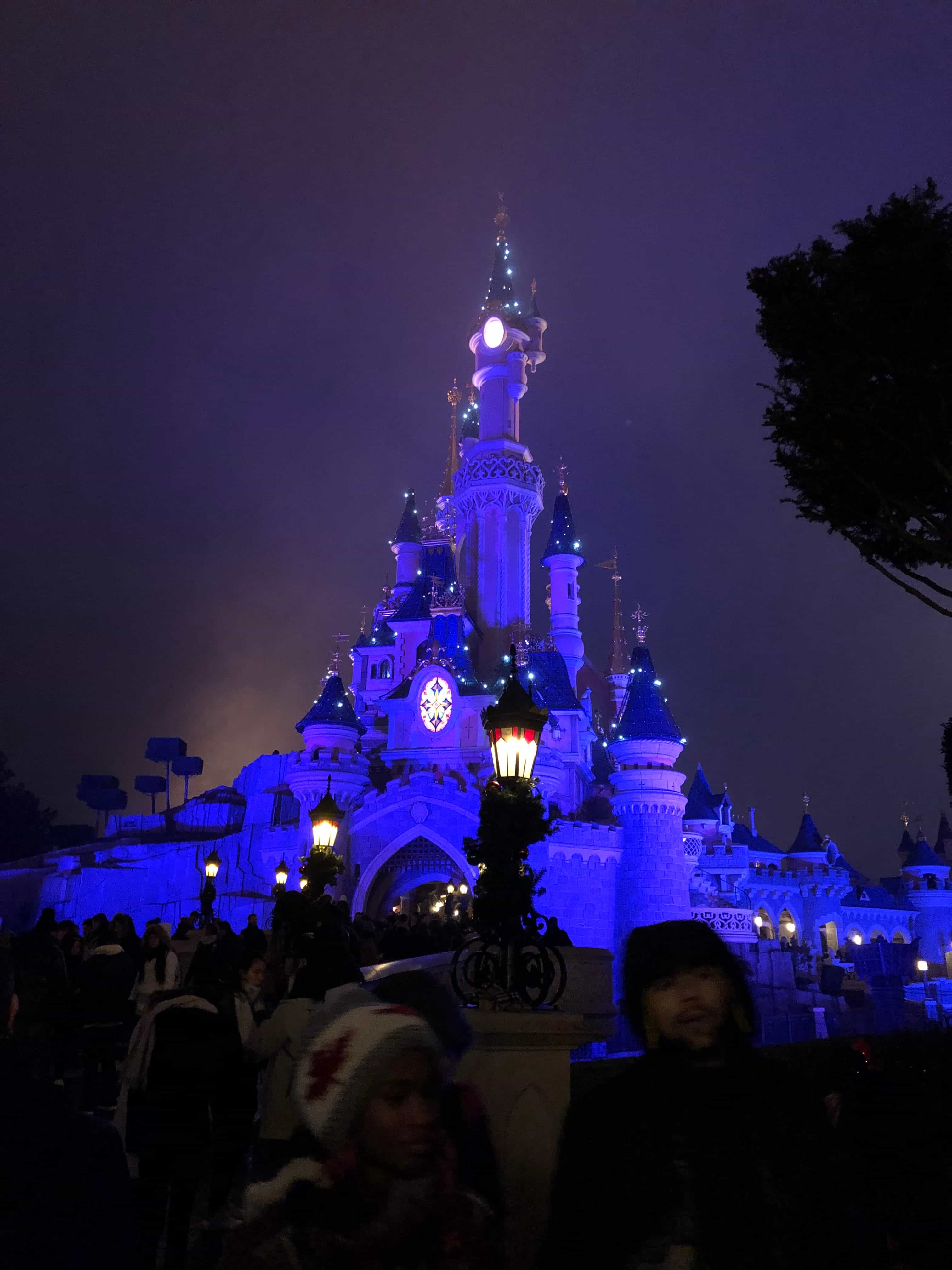 A Disney castle lit up with blue lights at night. 