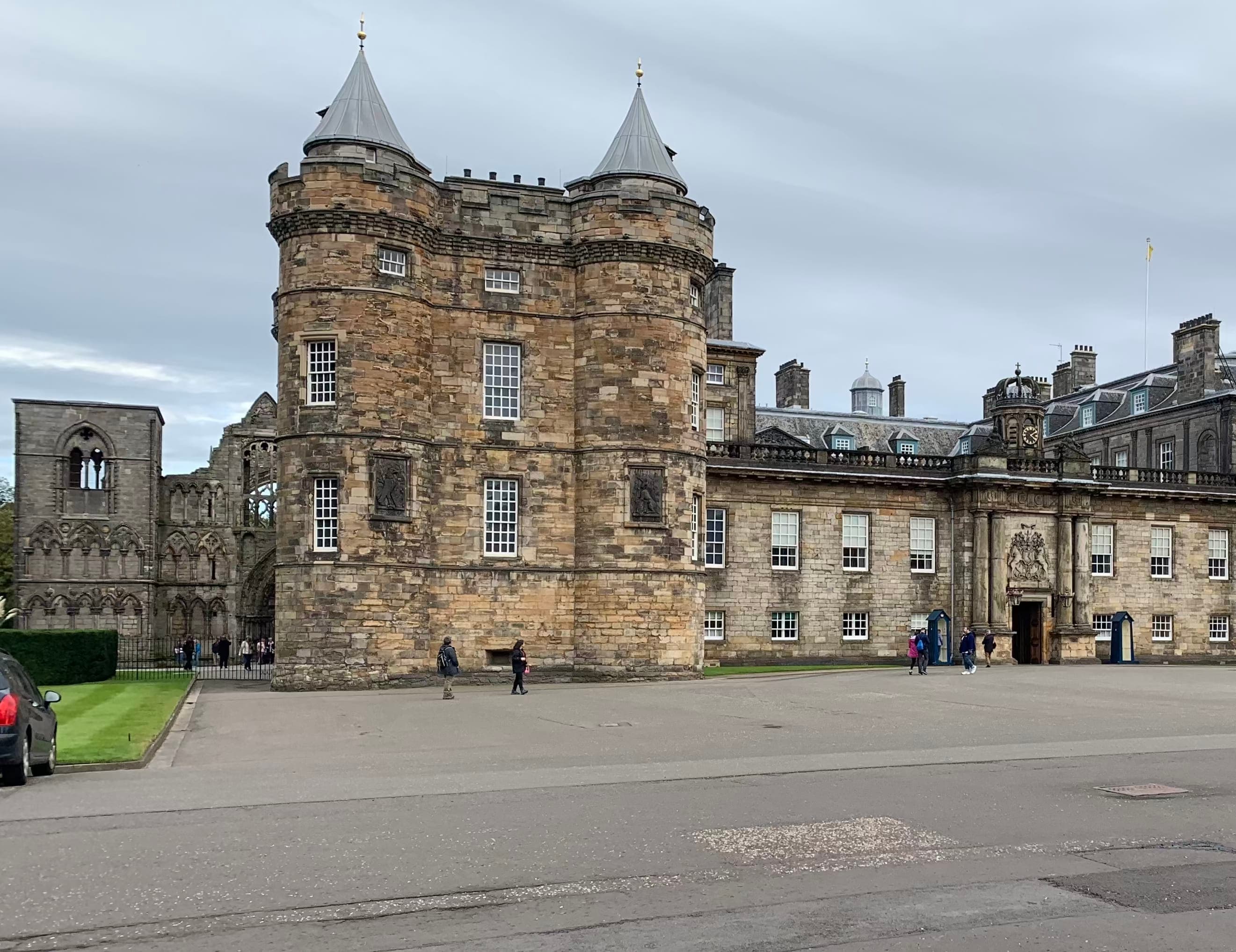 View of a large old building and plaza with pedestrians on a cloudy day