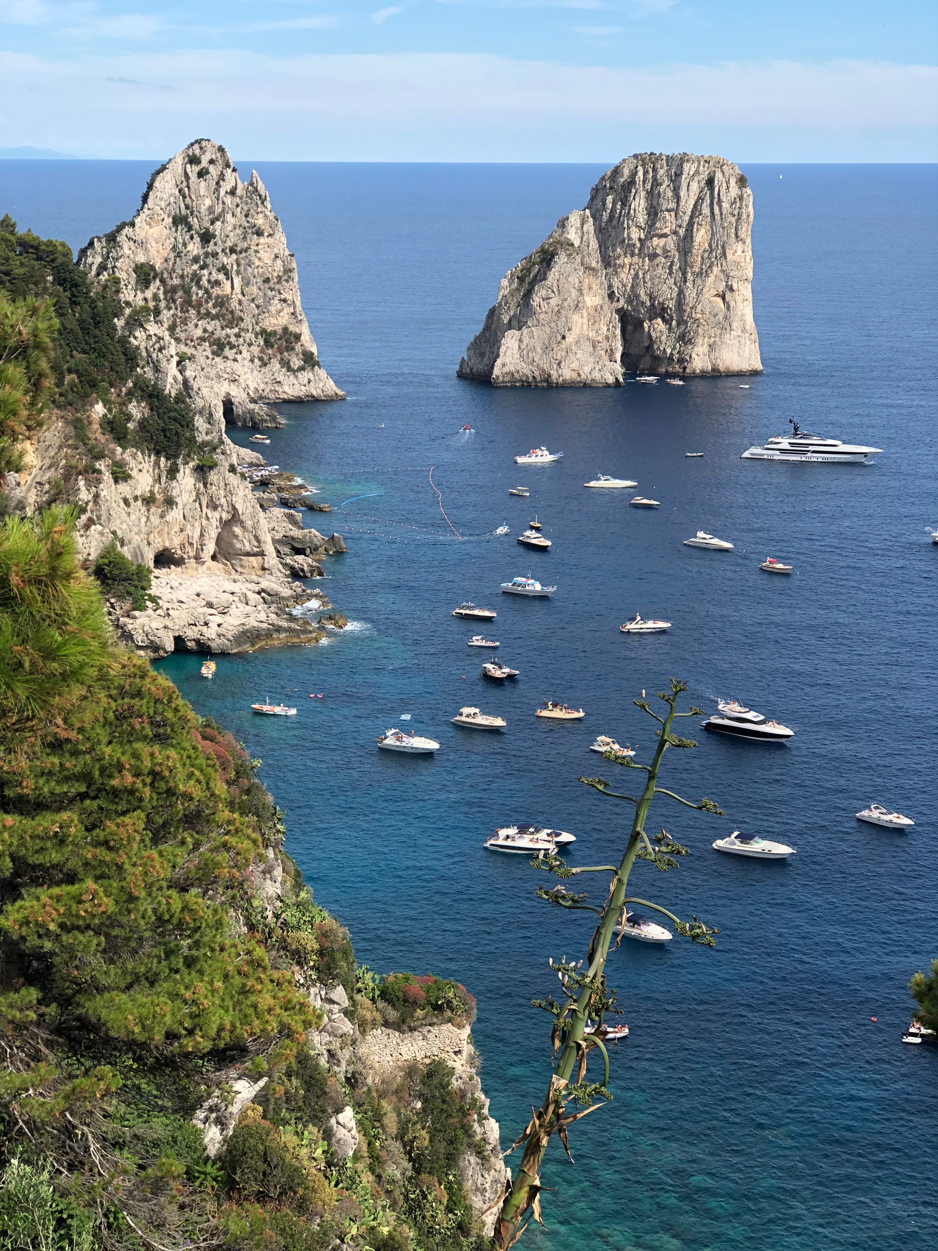 Aerial view of small boats at sea near Capri’s famous rock formations on a sunny day