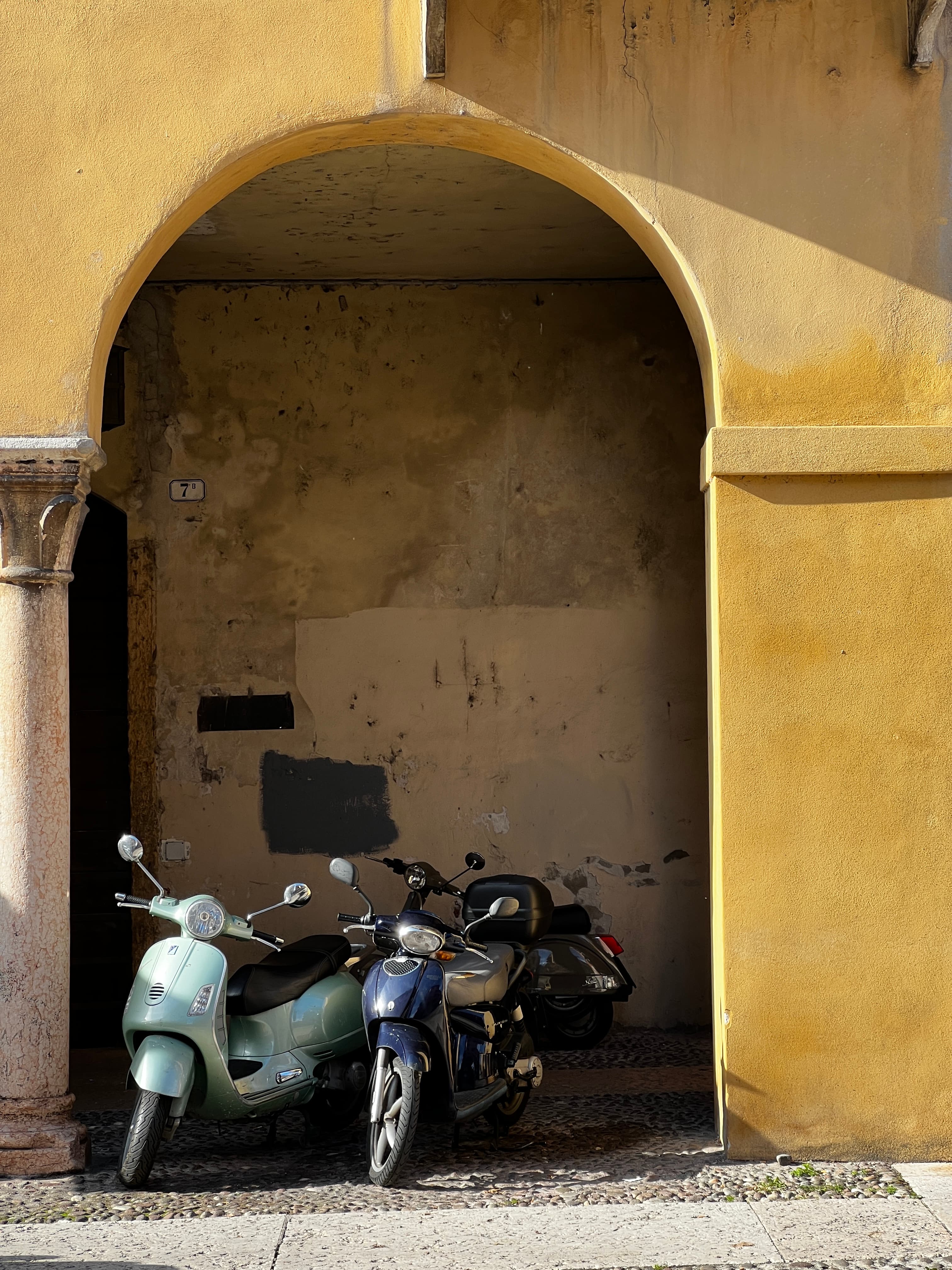 View of two scooters parked side by side underneath a yellow archway