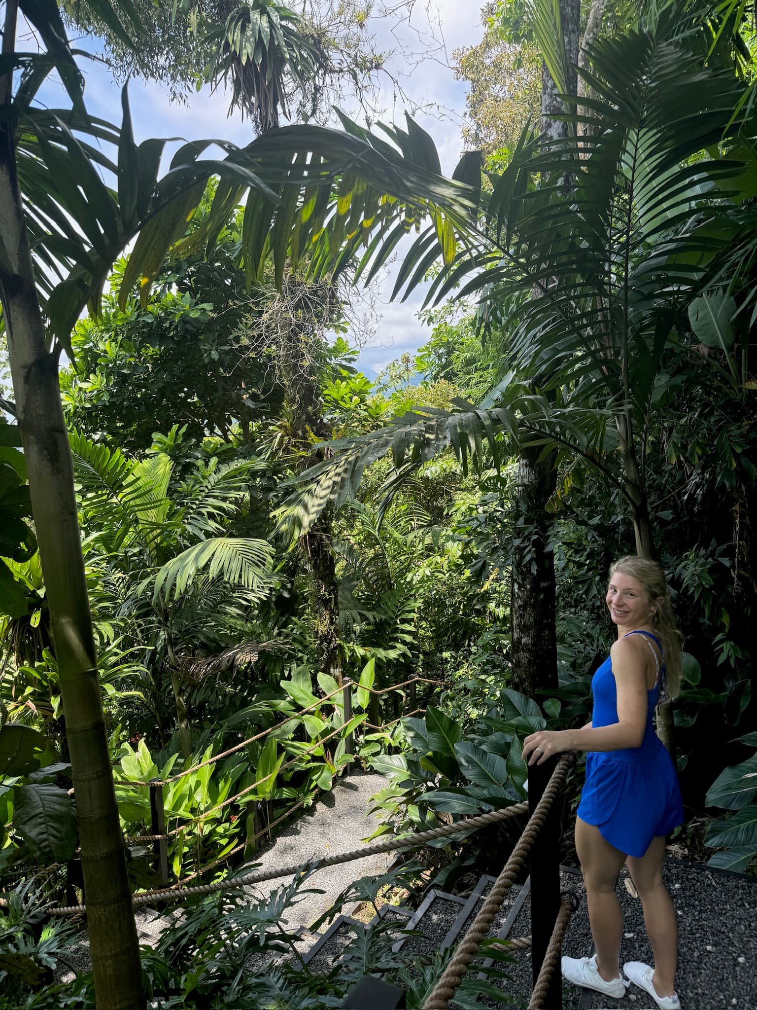 Cady in a blue dress walking through a lush green jungle environment on a sunny day