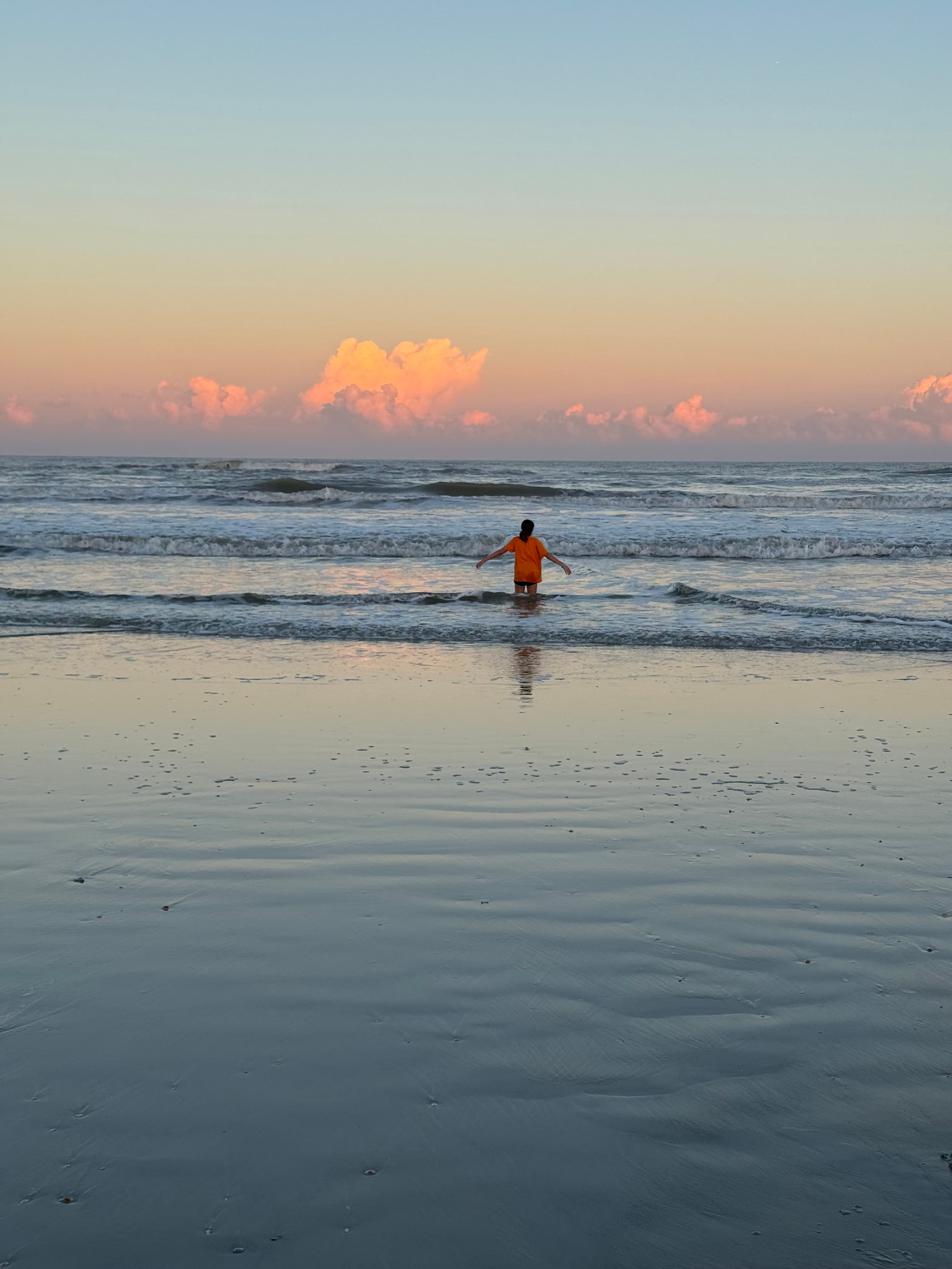 Beautiful view of Cady walking into shallow ocean water at sunset