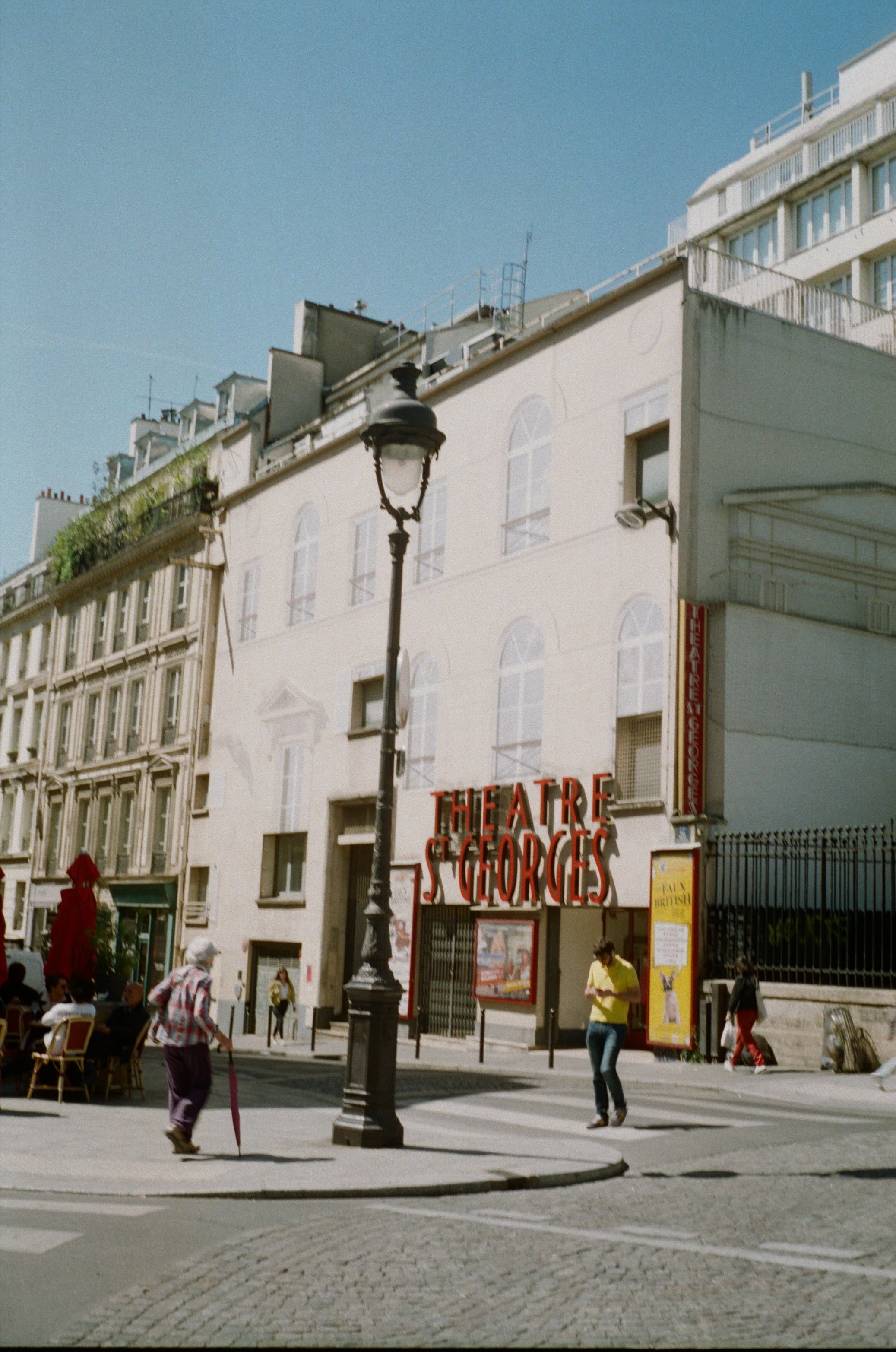 View of a white building on a mostly empty city street under clear skies