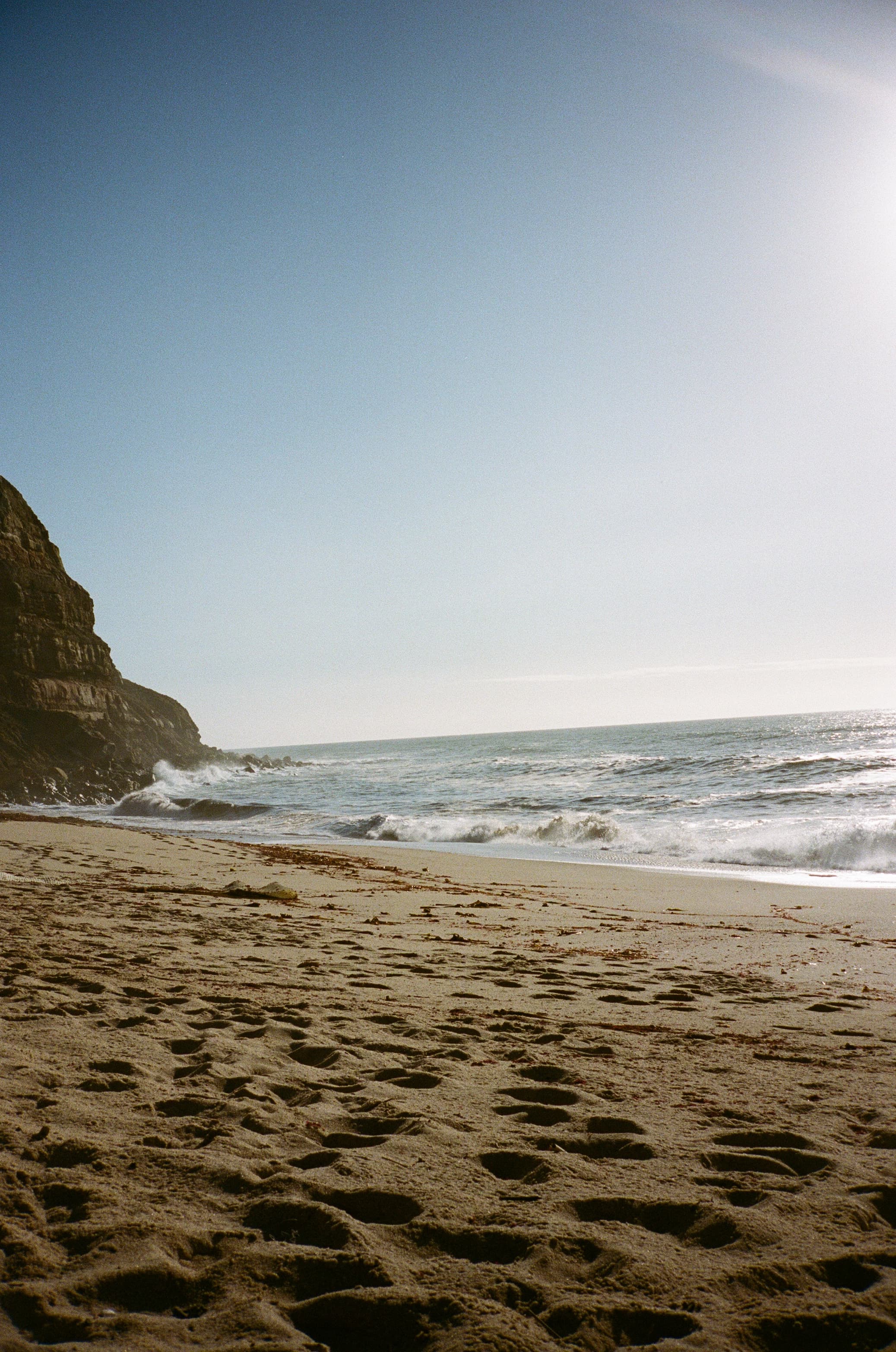 Beautiful view of an empty beach and waves crashing ashore under clear skies