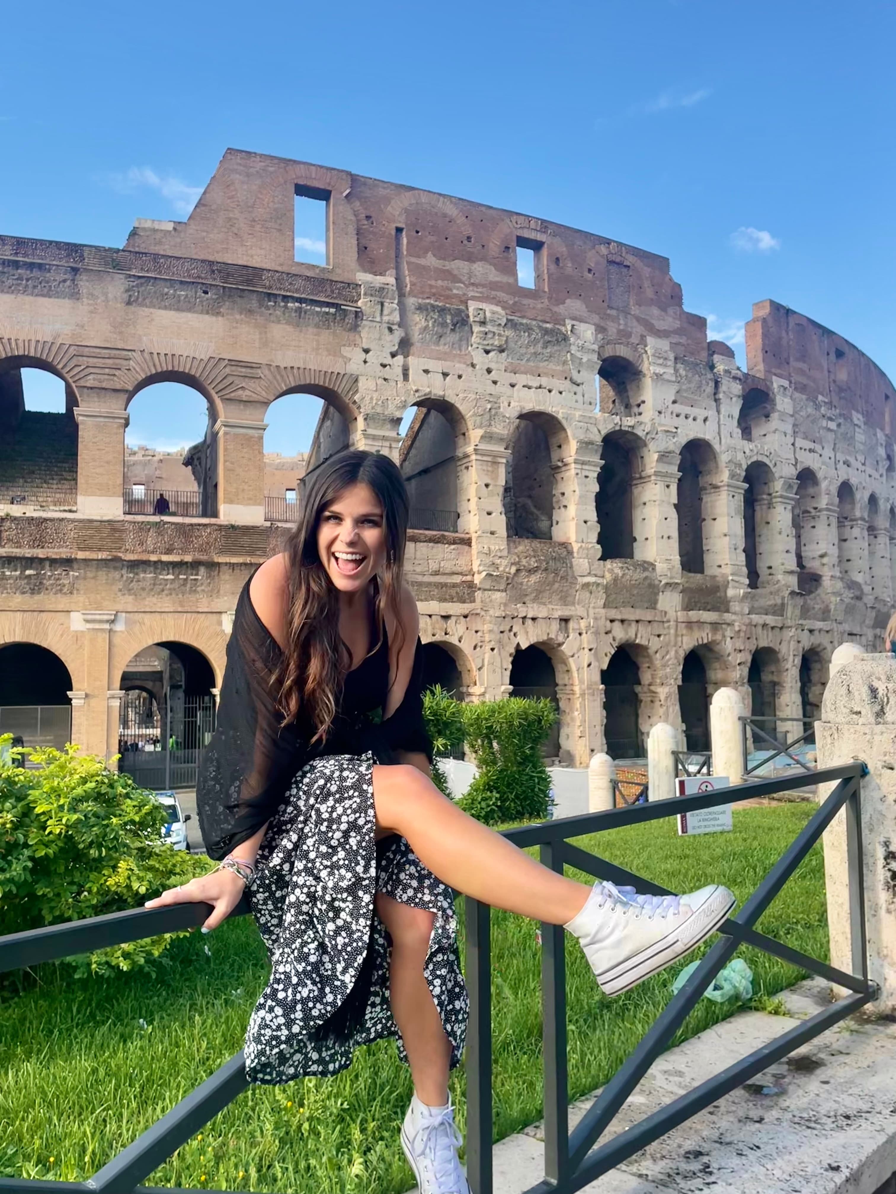 Advisor posing leaning against a railing with an ancient building in the background.