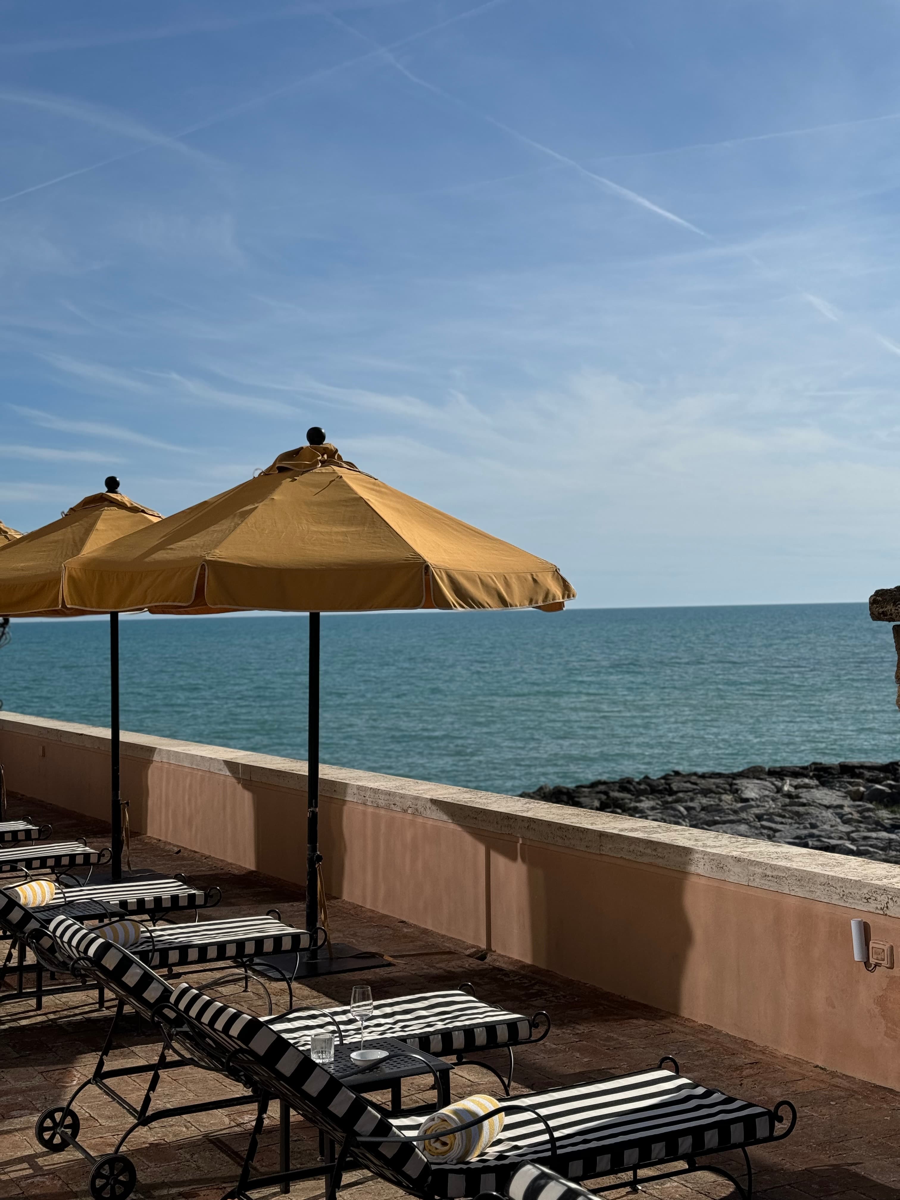 View of lounge chairs and yellow umbrellas looking out over the sea on a sunny day