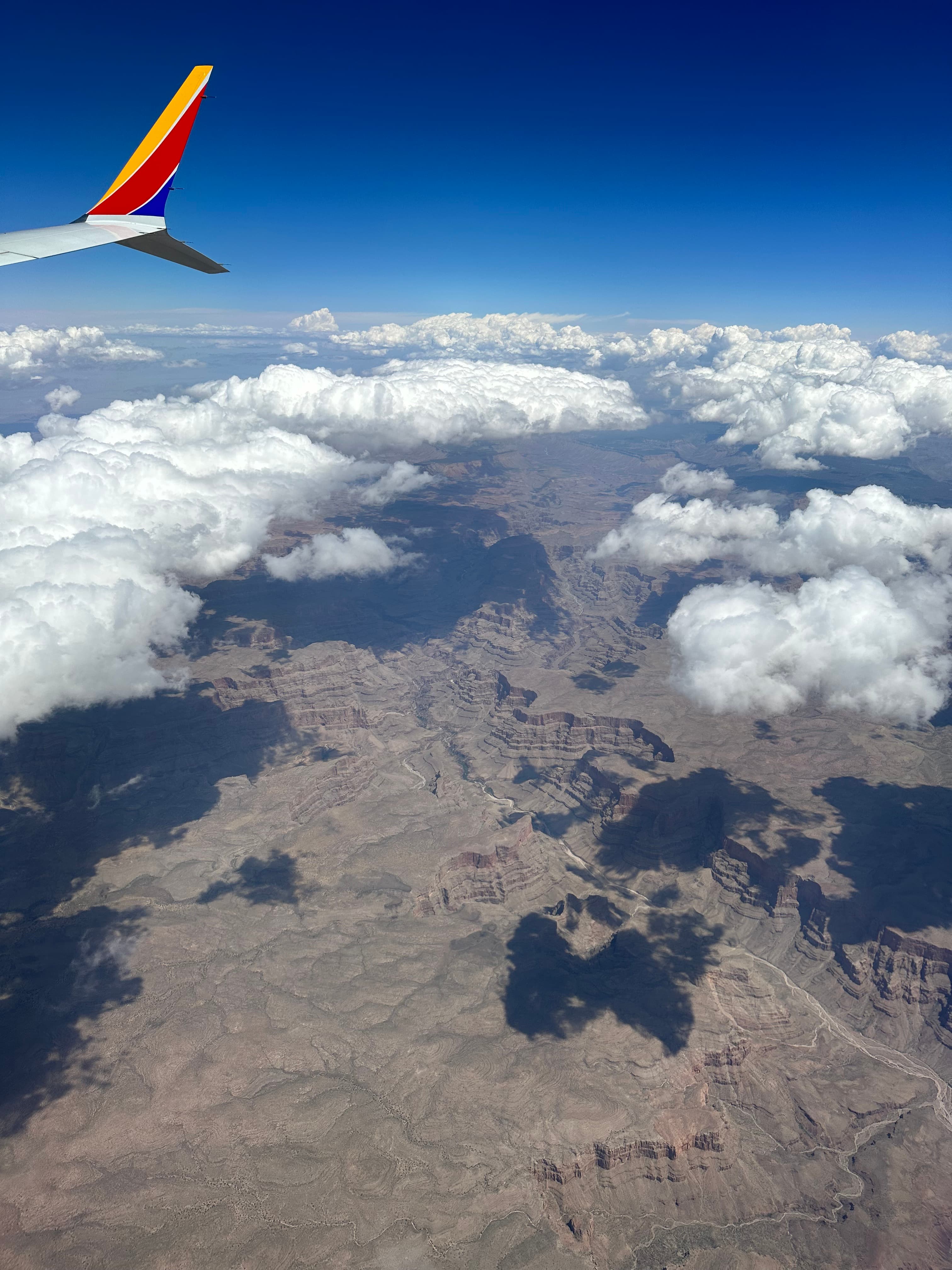 View of a mountainous landscape and small clouds seen from a plane window
