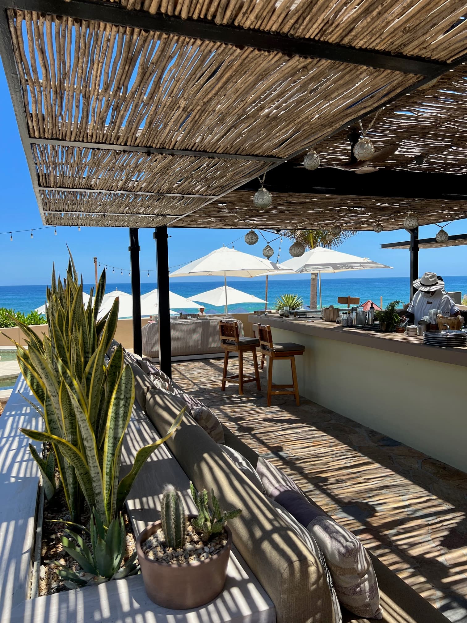 View of a resort bar covered by a thatched roof overlooking the sea on a sunny day