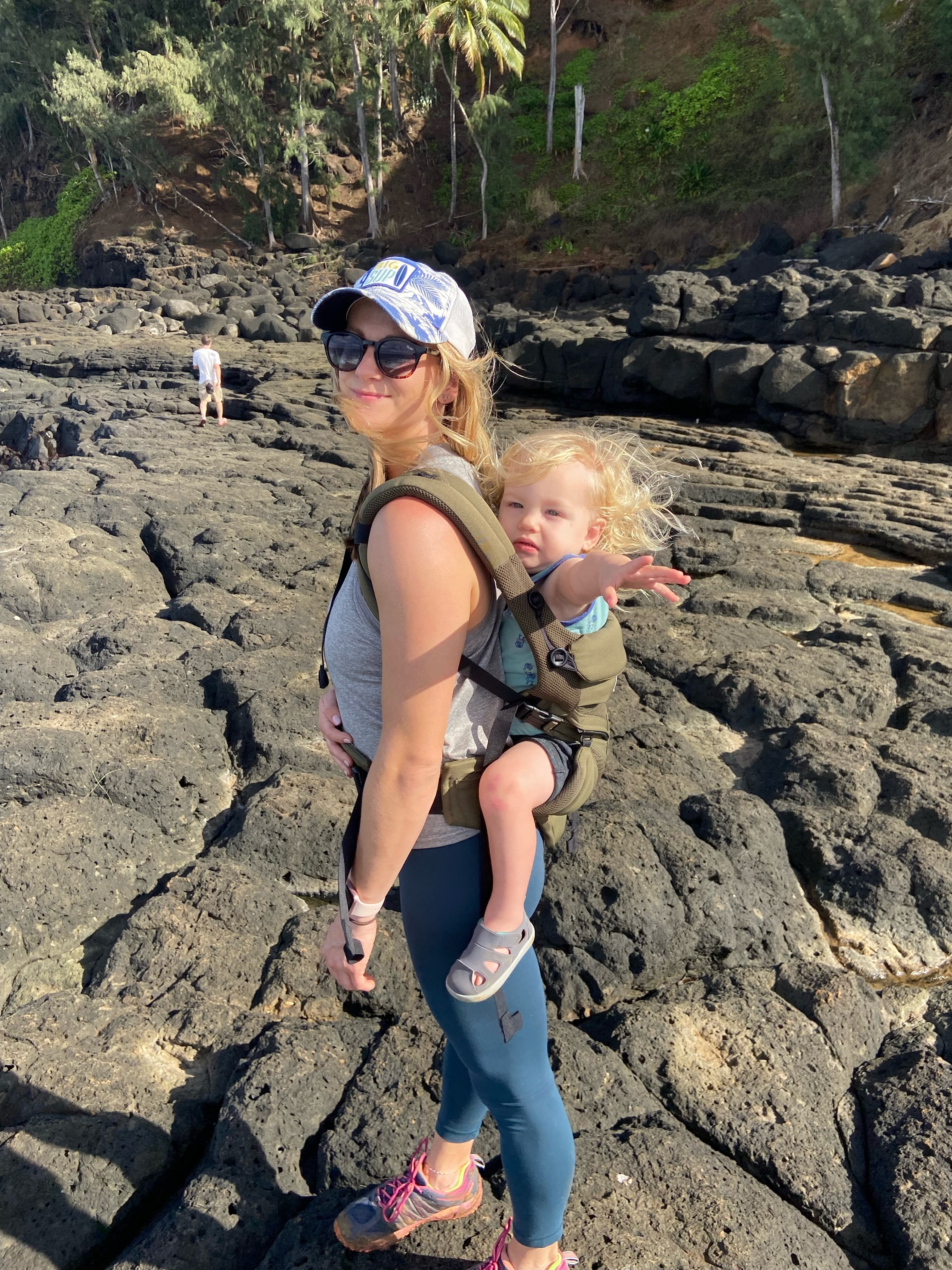 Advisor with a baby strapped to her back on a rocky landscape 
