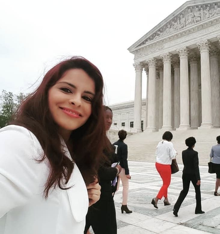 Melissa in a white blazer taking a selfie in front of a government building in Washington DC