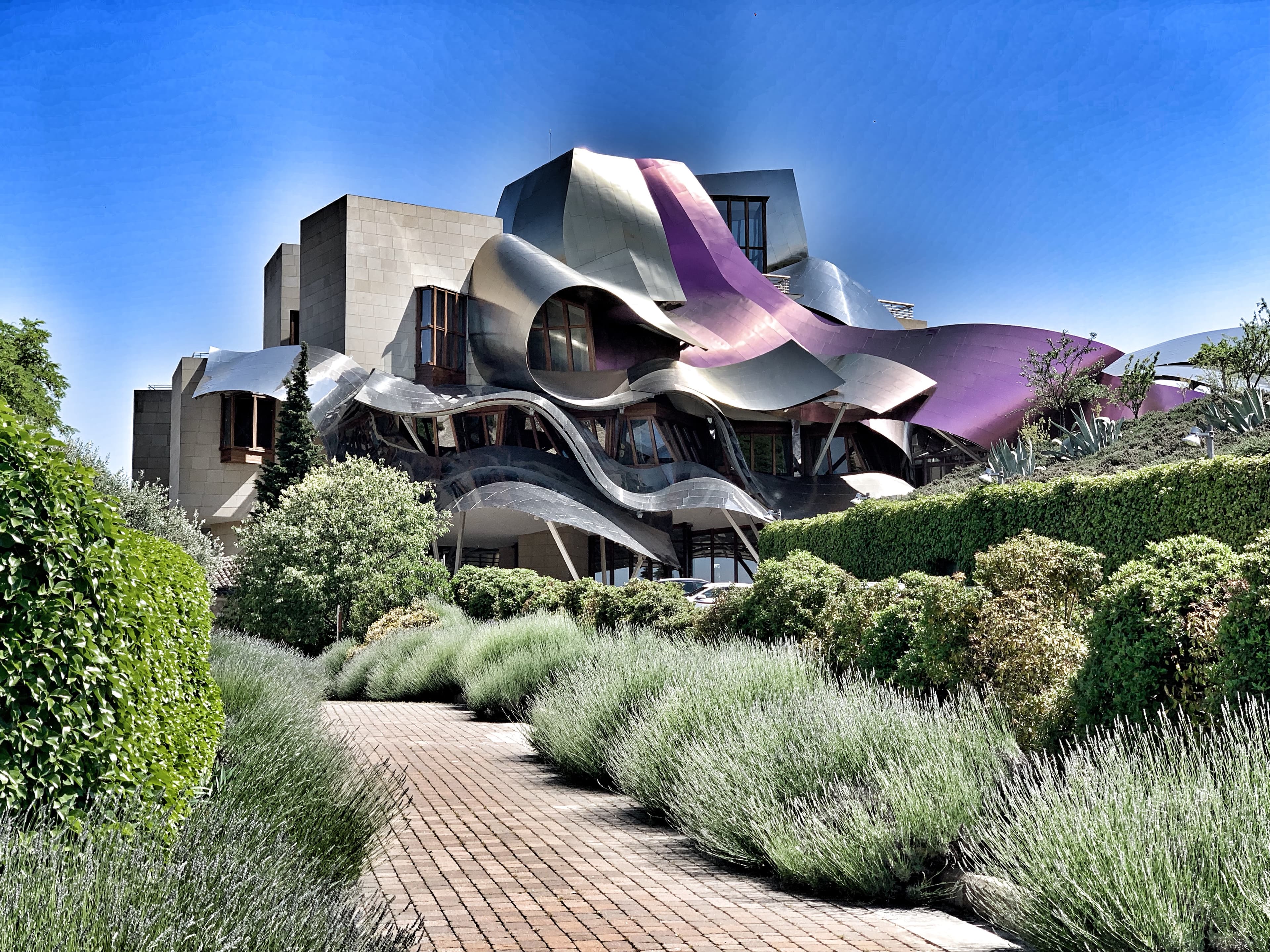 A modern architectural building surrounded by dense foliage on a clear day. 