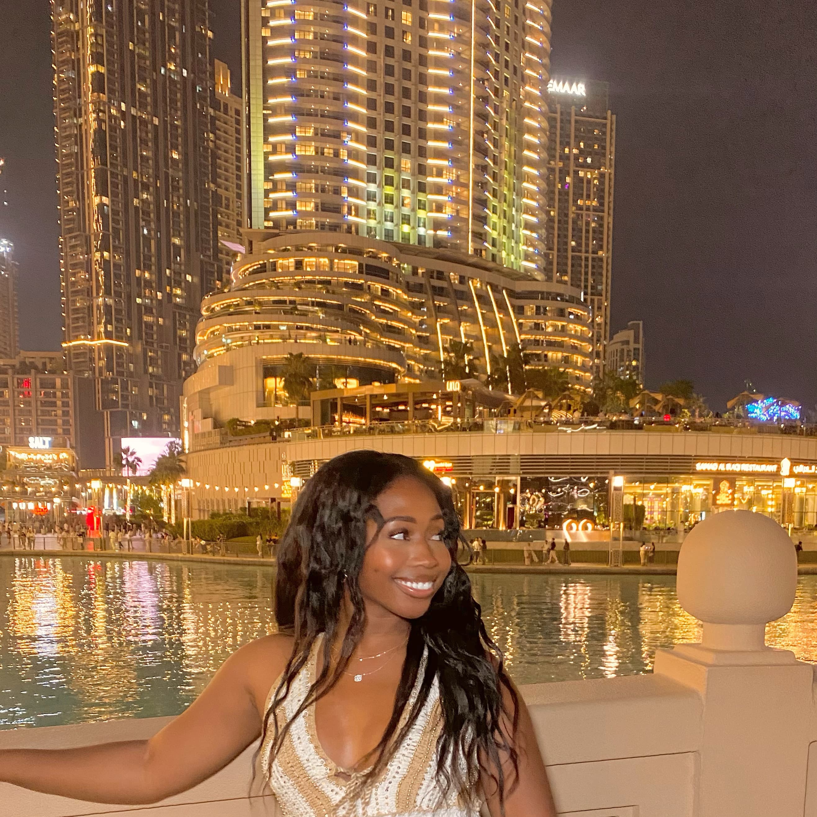 View of advisor posing in front of a large fountain and brightly lit hotel buildings at night