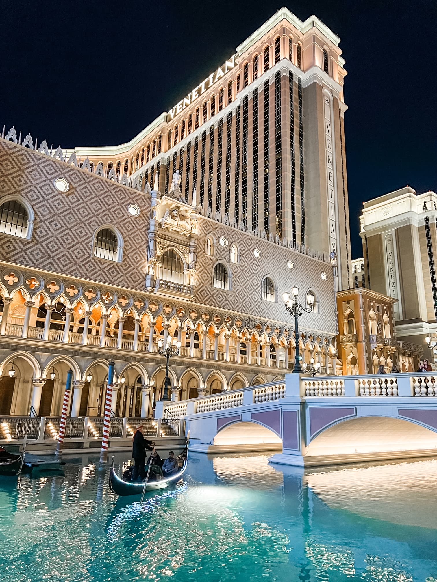 View of a large Las Vegas hotel lit up at night with a pool in front
