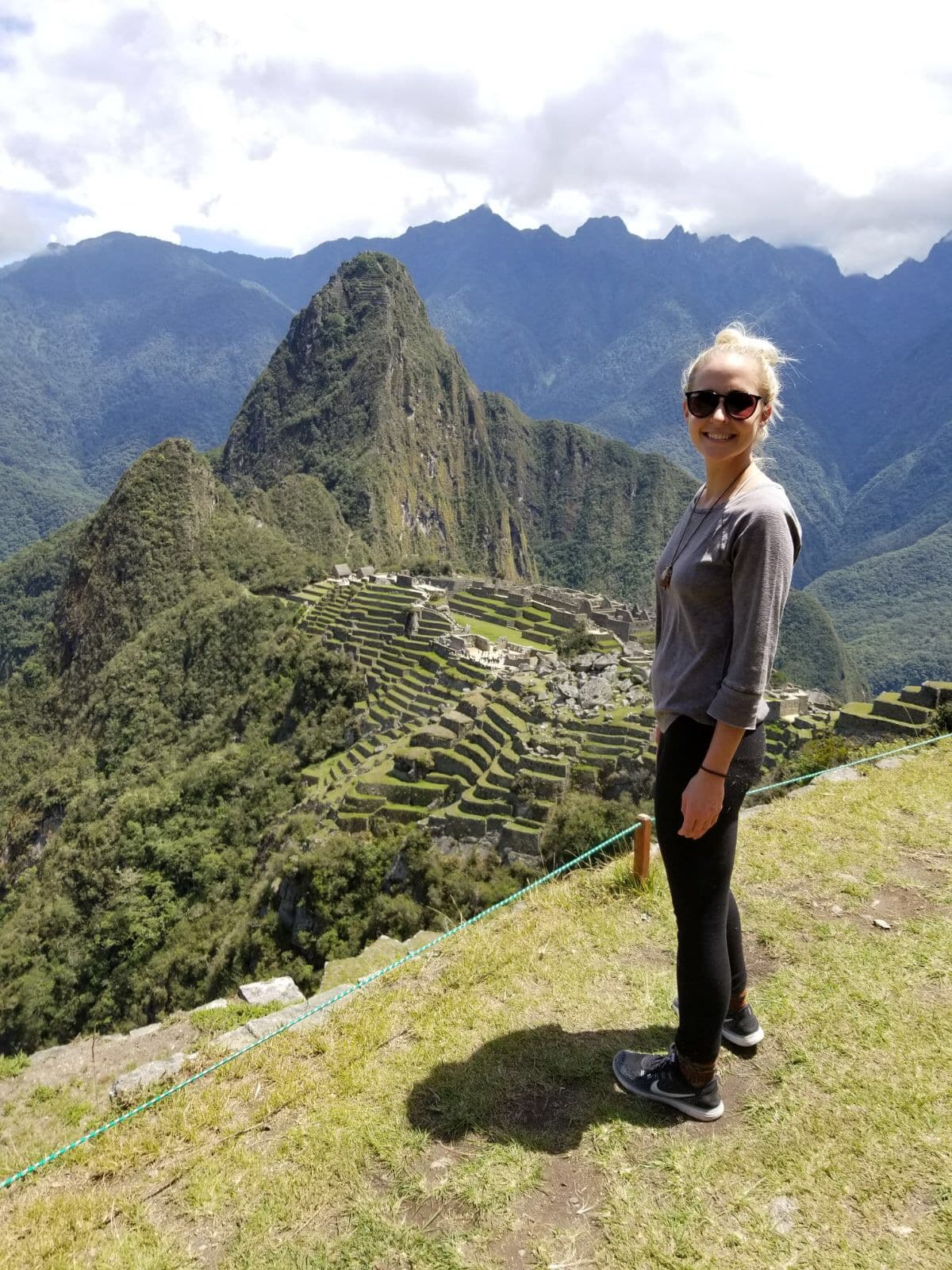 Travel advisor Kristen standing on a grassy hill in front of the famous site of Machu Picchu