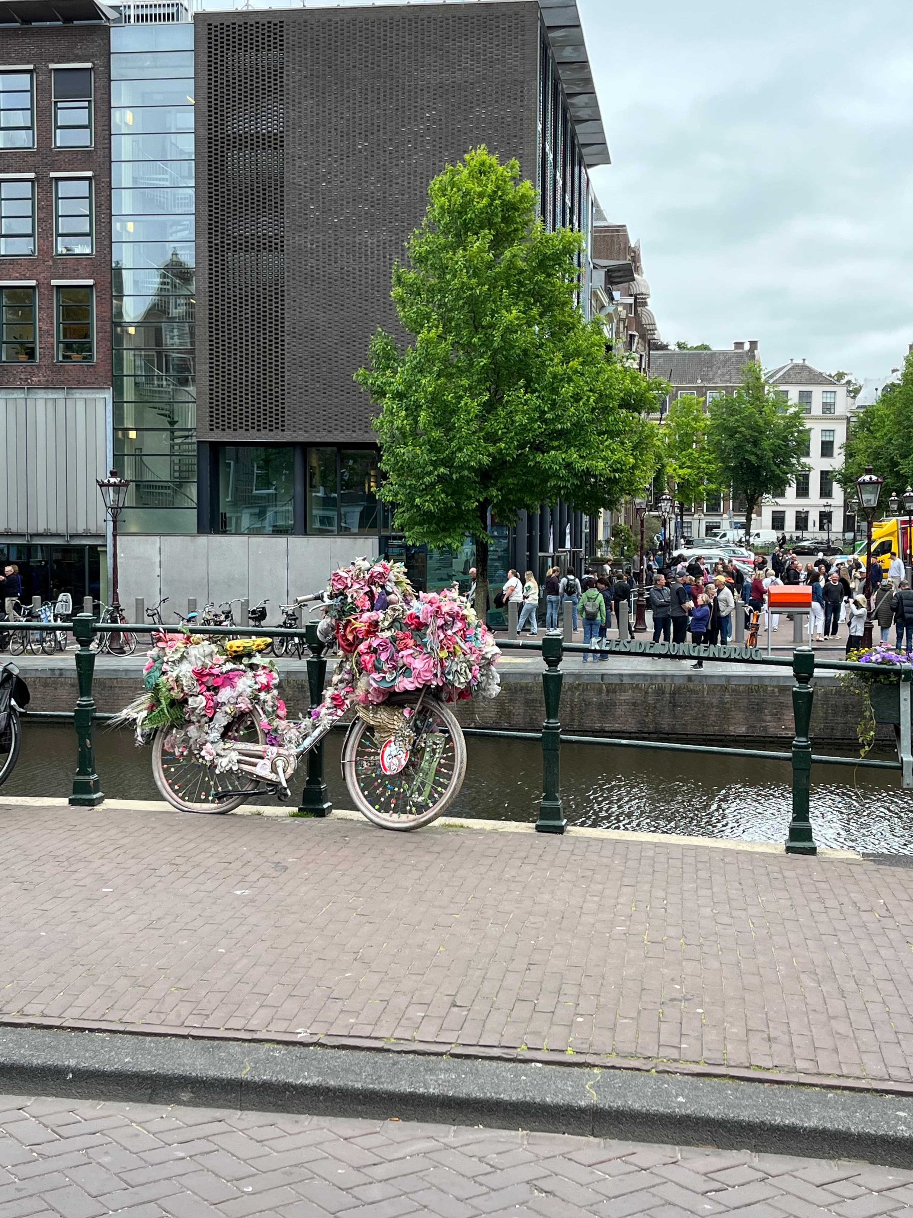 View of a bike decorated with flowers by a canal in Amsterdam on a cloudy day