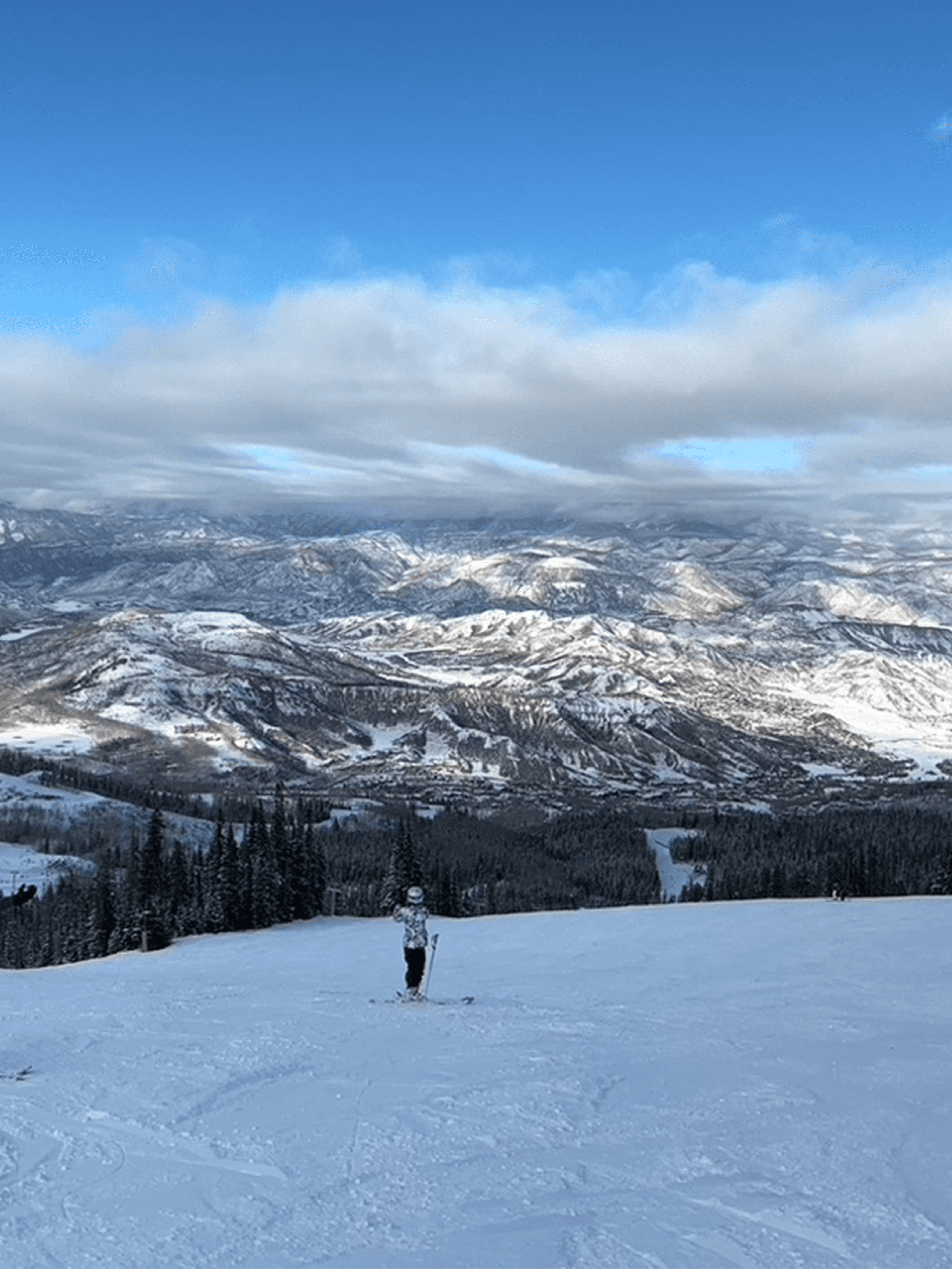View of a person skiing on an empty slope with mountains visible in the distance