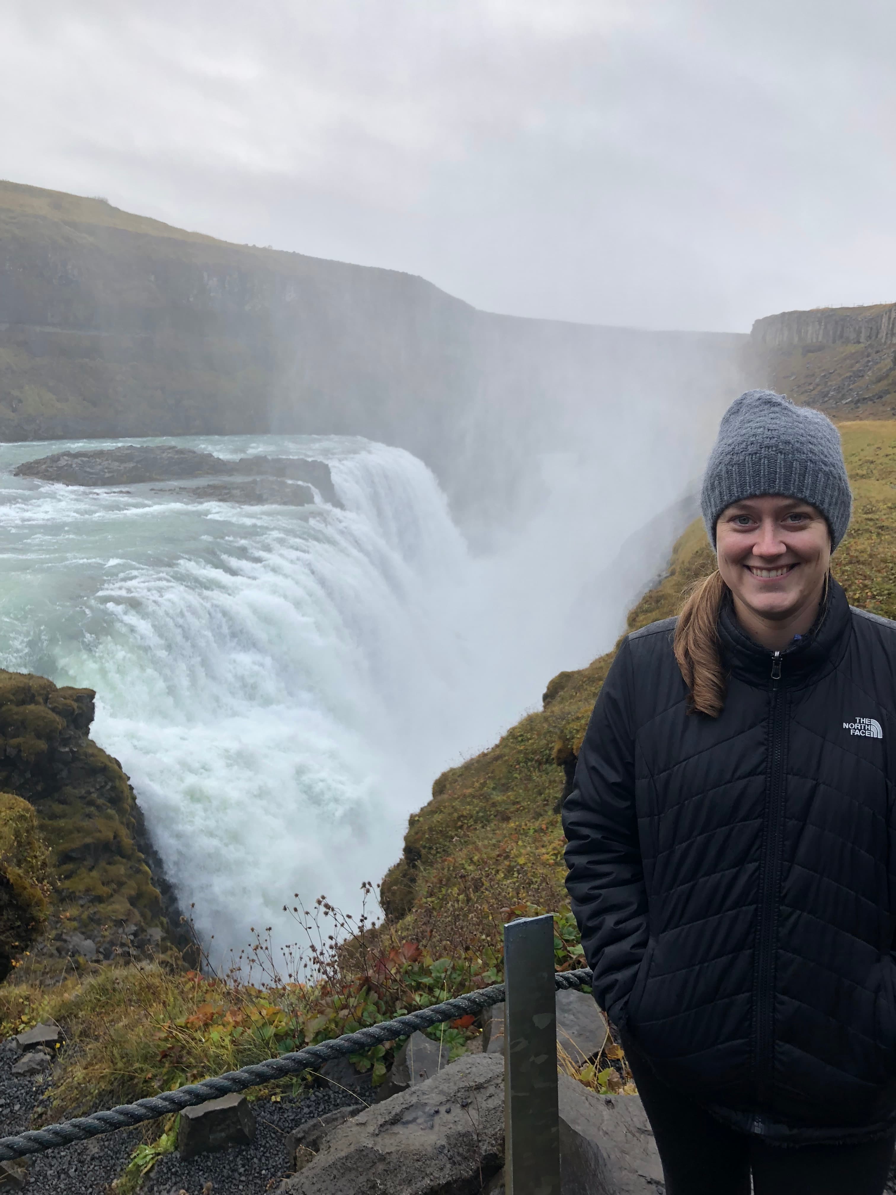 Advisor standing on a cliff in front of a waterfall.