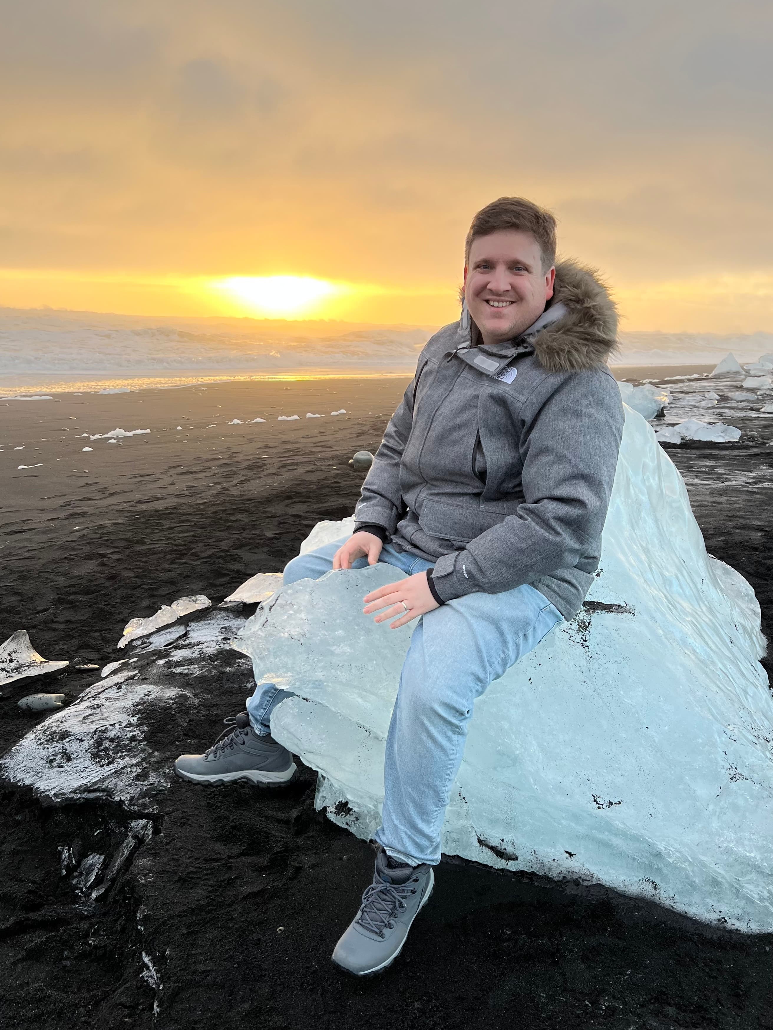 Advisor posing on an icy stretch of beach as the sun sets behind the clouds. 