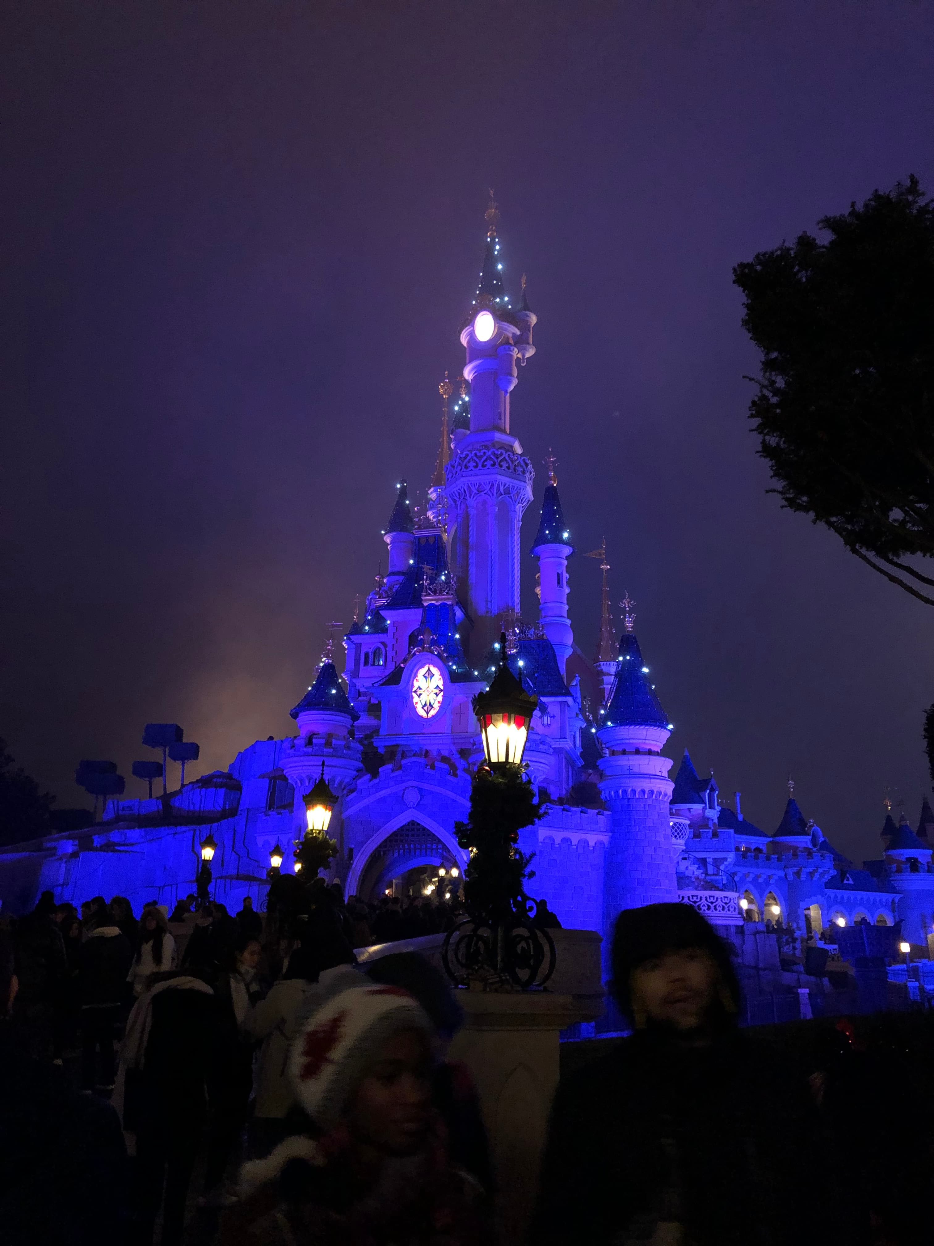 A Disney castle lit up with blue lights at night. 