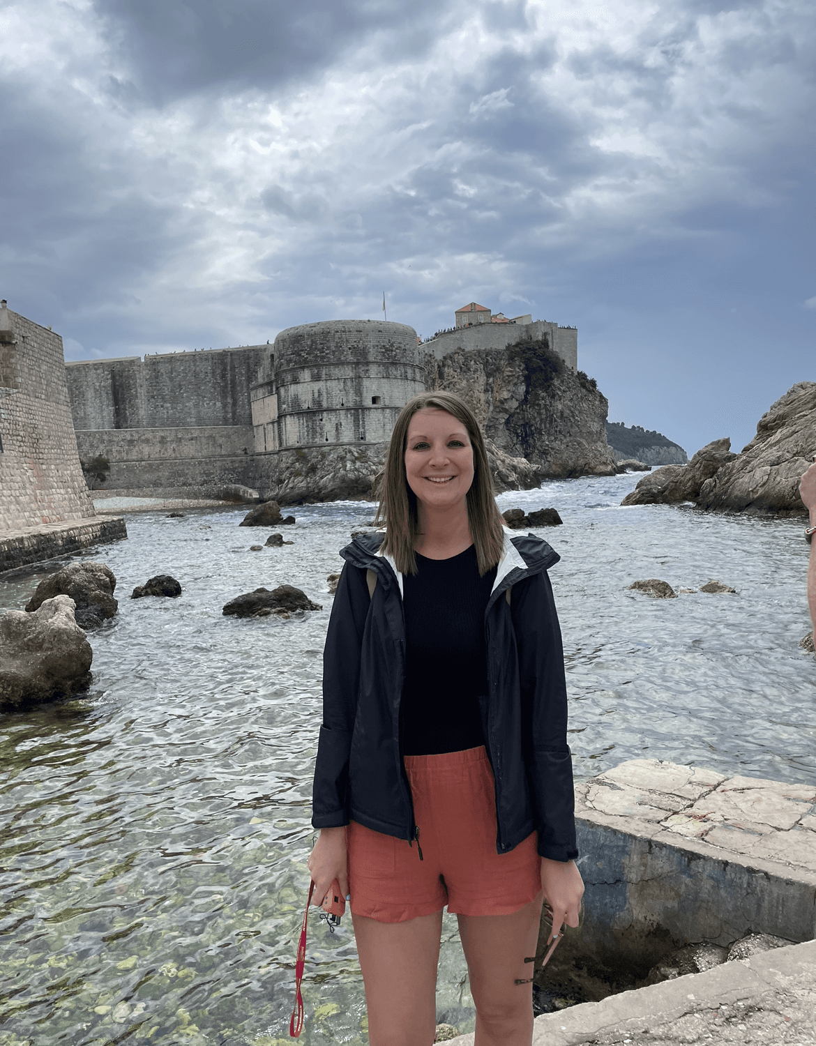 Advisor posing for an image with the ocean in the distance during the daytime. 