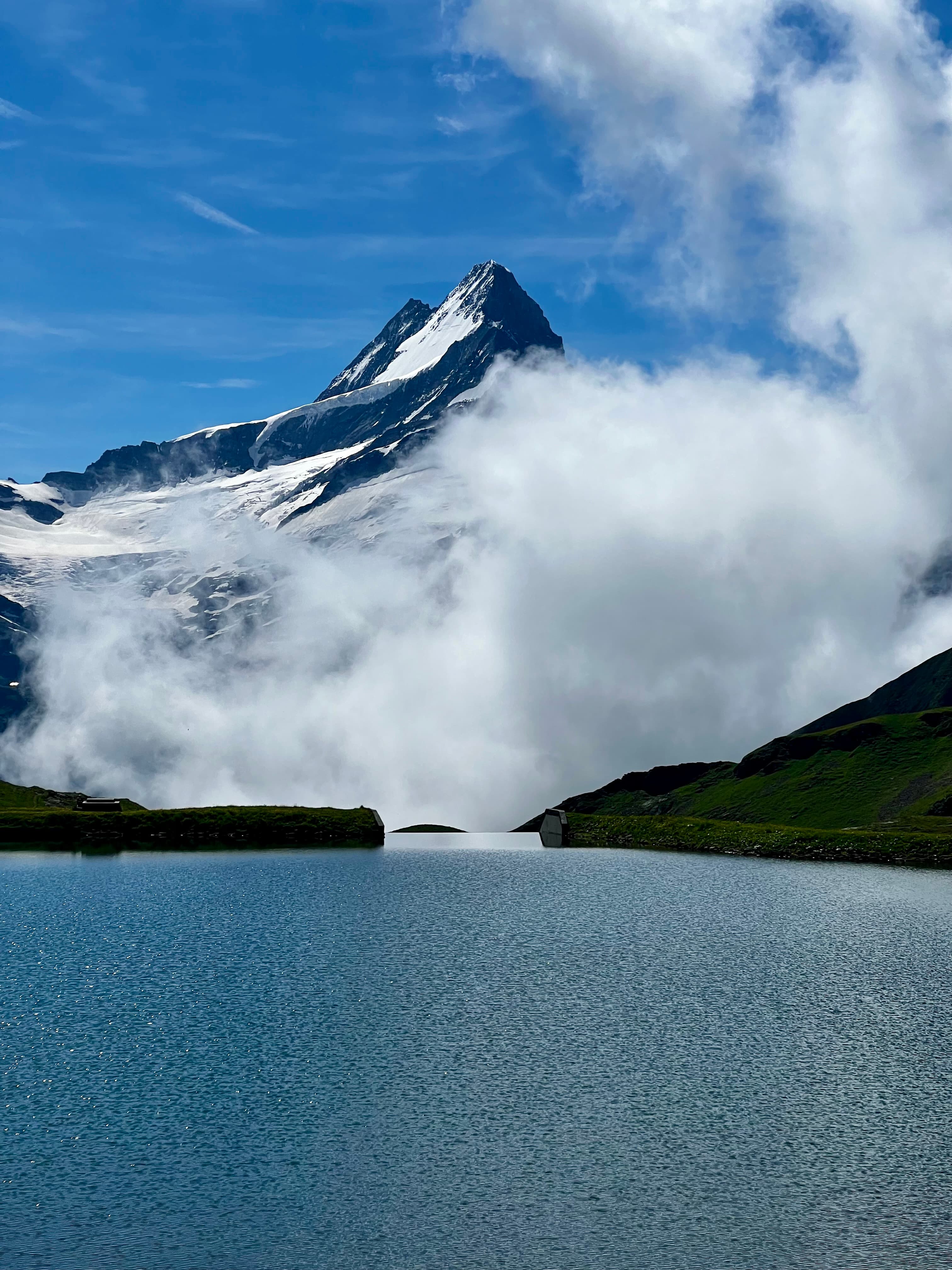 View of a low-hanging cloud in front of a snowy mountain beside a lake