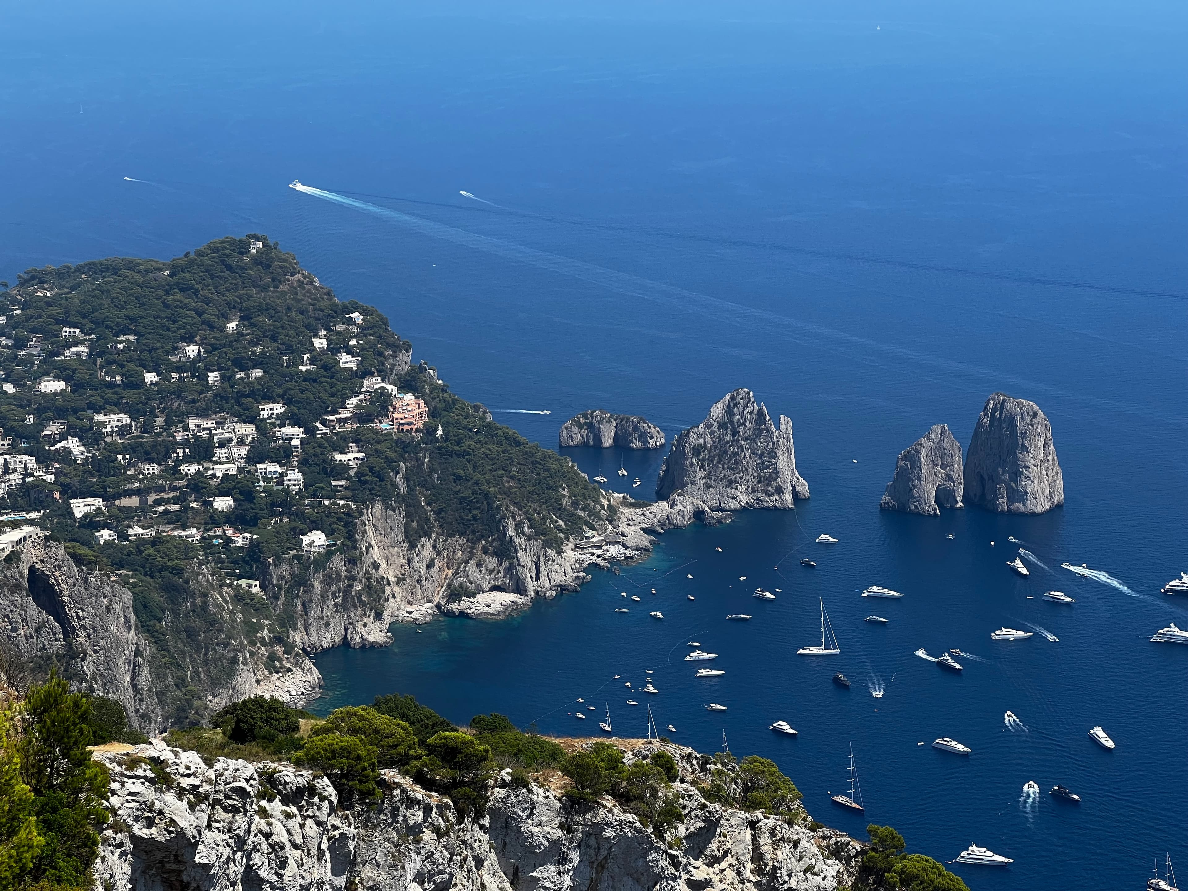 Aerial view of a rocky coastline and many small boats docked offshore