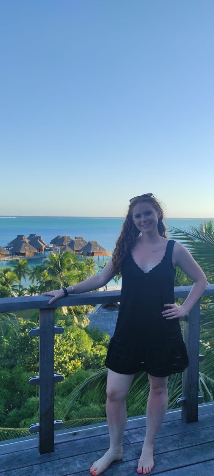 Advisor in a black dress on a balcony overlooking the sea on a sunny afternoon