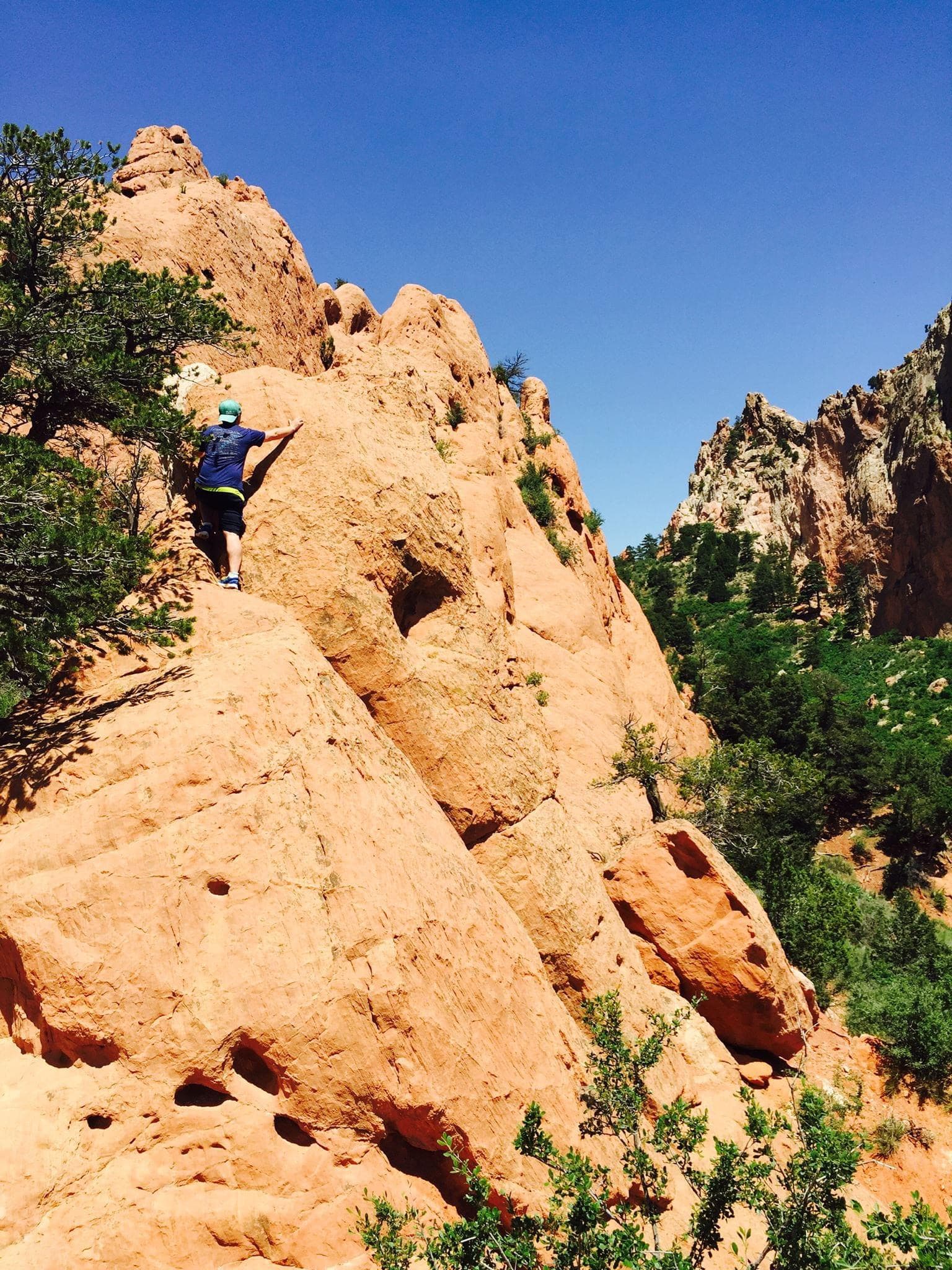 View of a person climbing rocks on a hike on a sunny day