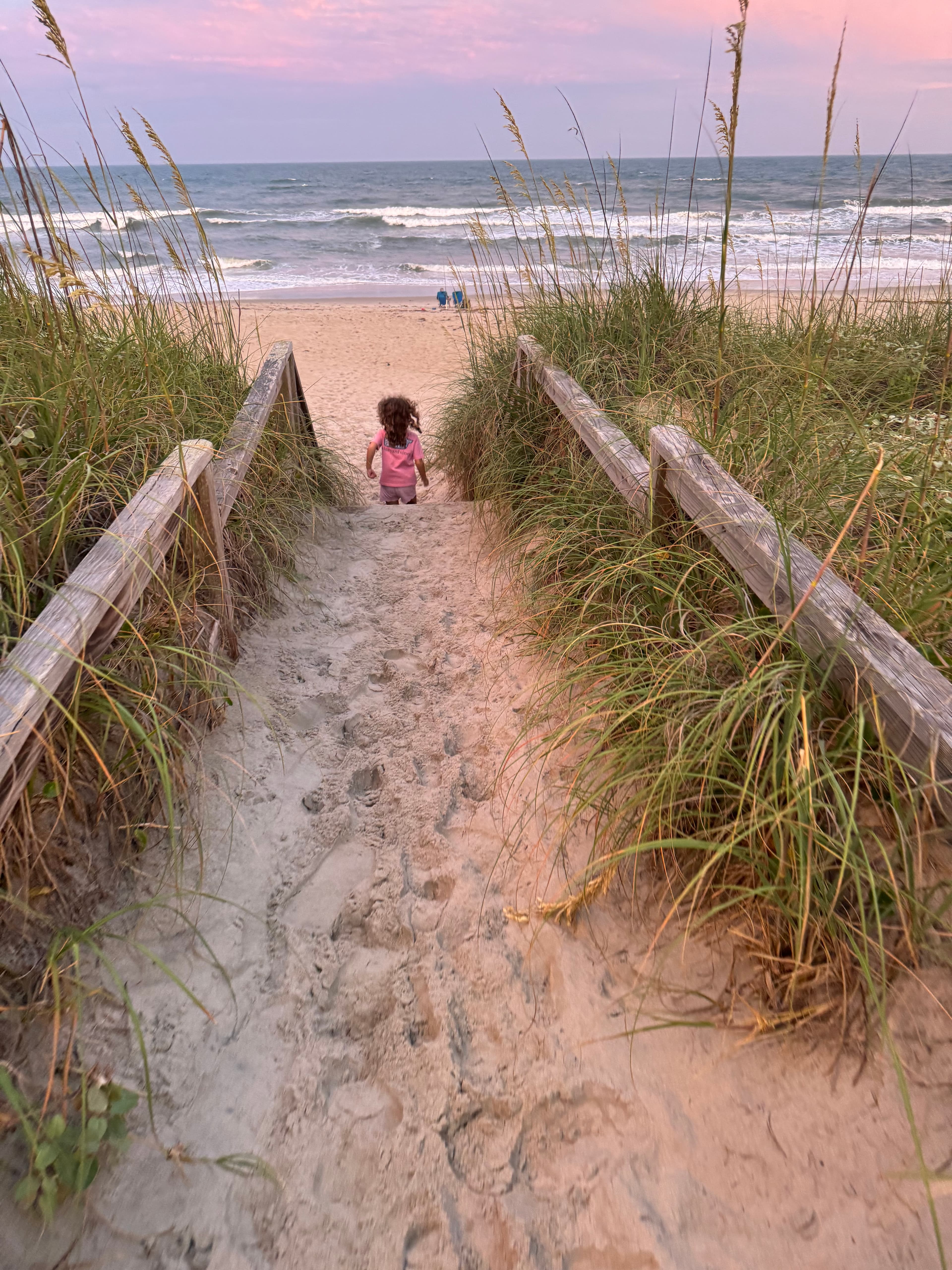 View of a sandy path leading to the sea at sunset