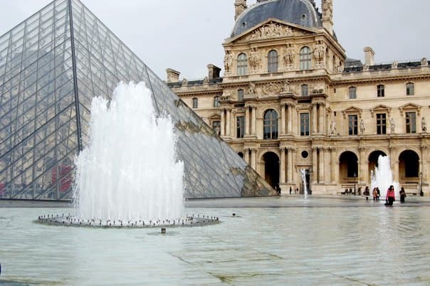 A glass pyramid shaped structure in front of a palace building