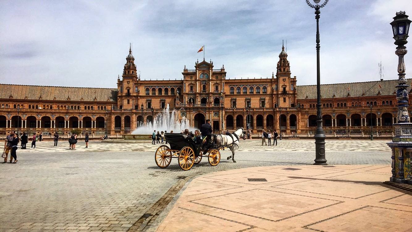 A horse-drawn carriage in a courtyard in front of a wide palace building