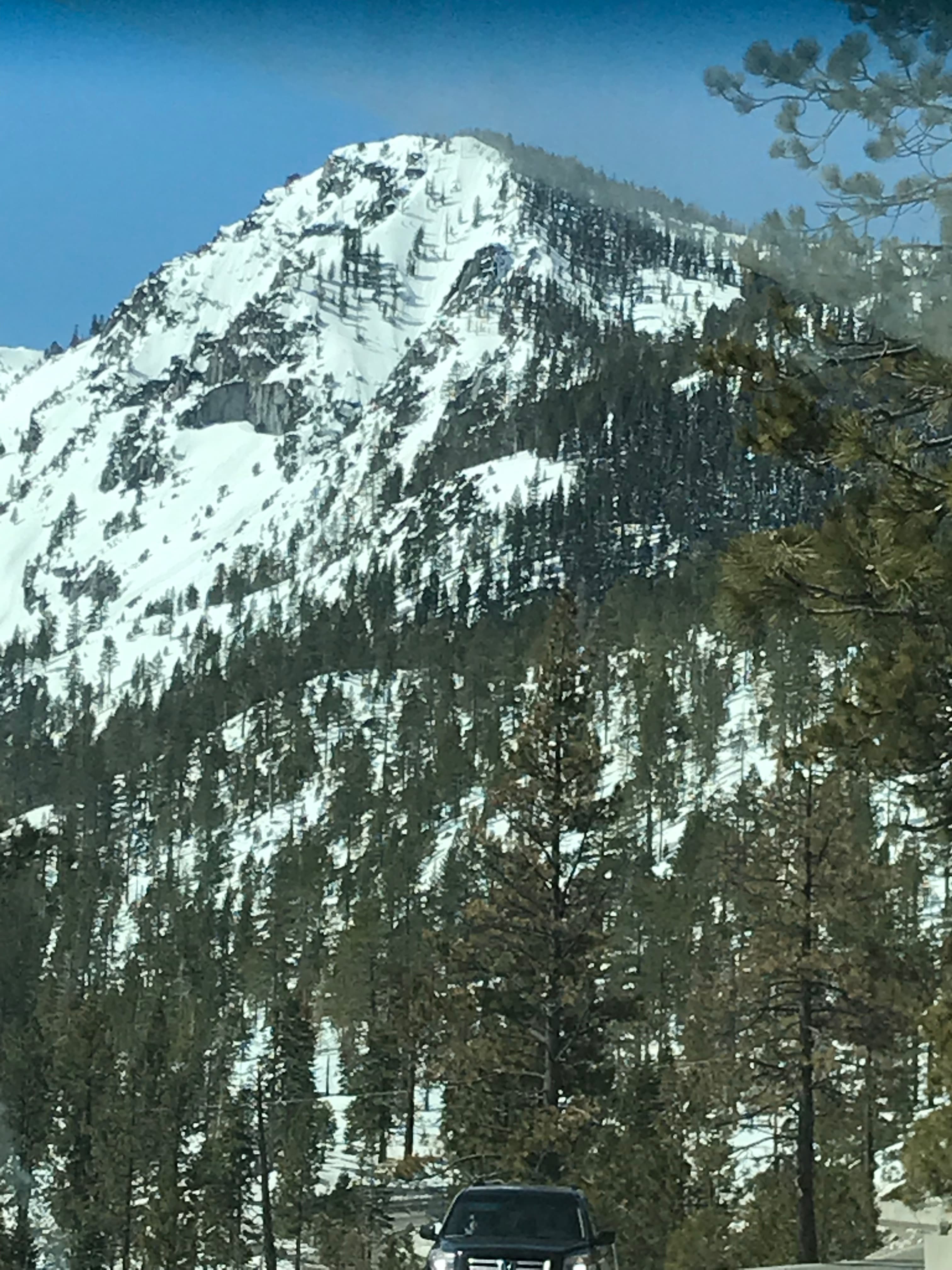 A snow-capped mountain stands tall against a clear sky.
