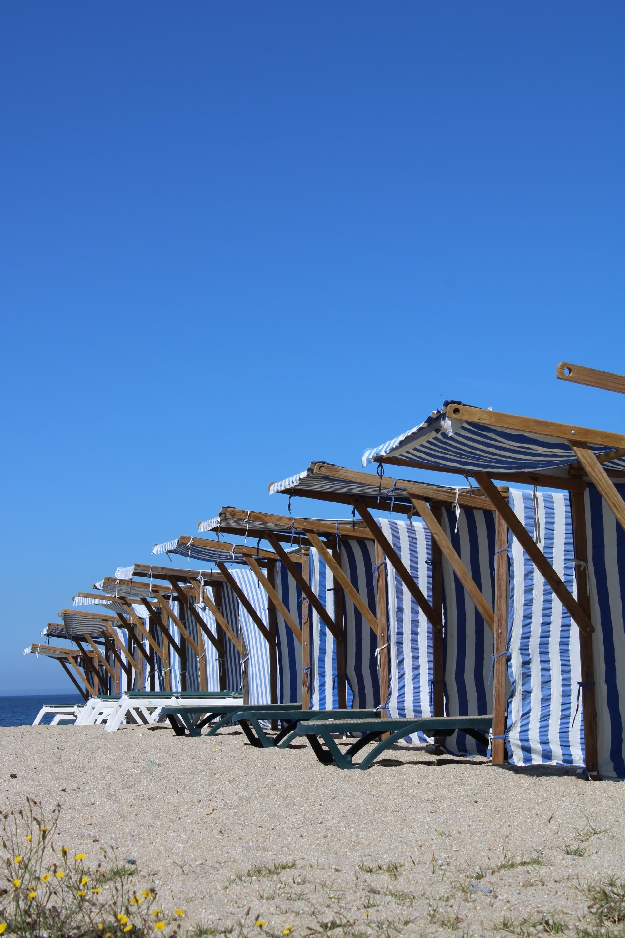 A pair of blue and white striped beach chairs arranged on a sandy beach