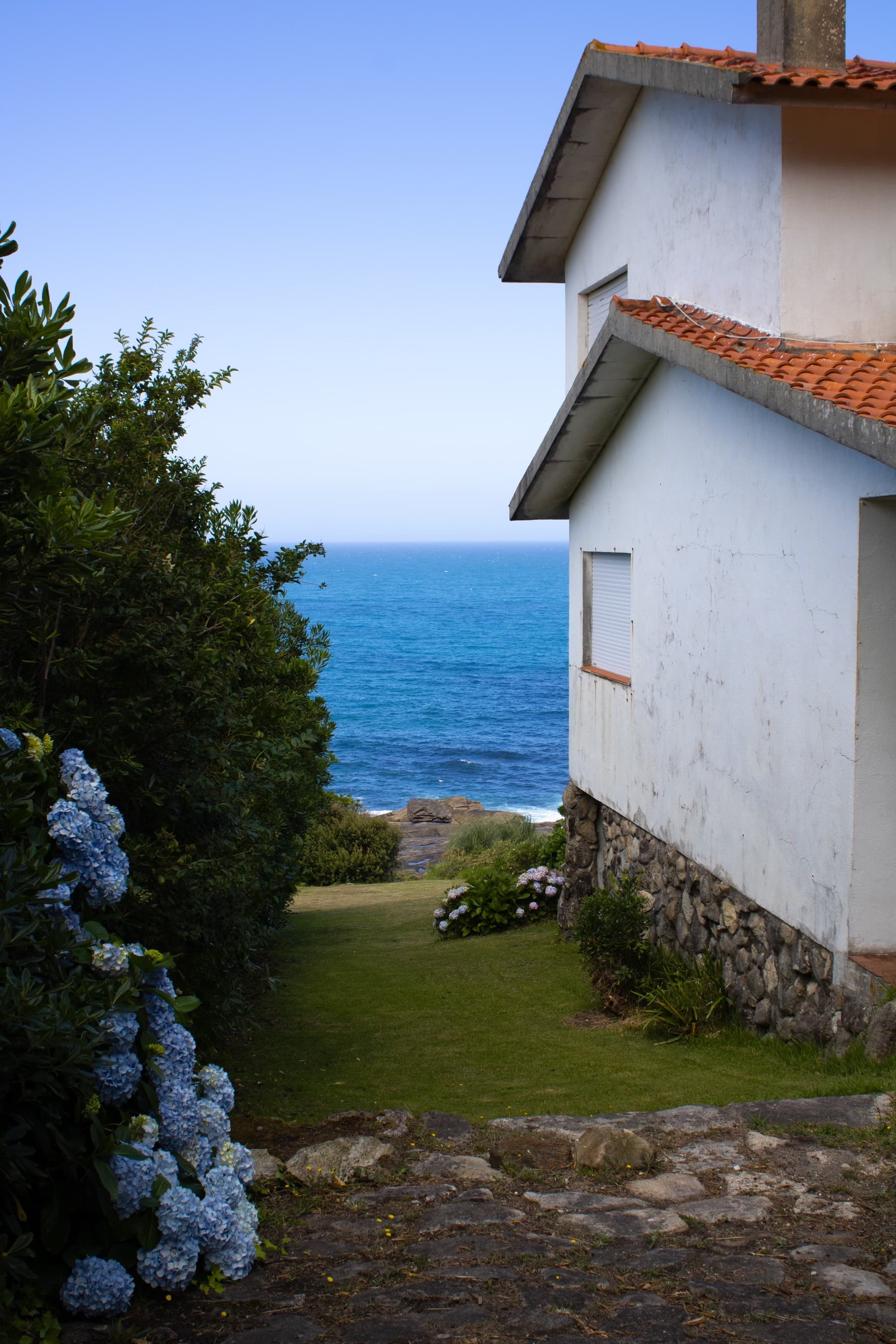 A charming house featuring a vibrant red roof, with a view of the ocean in the background.