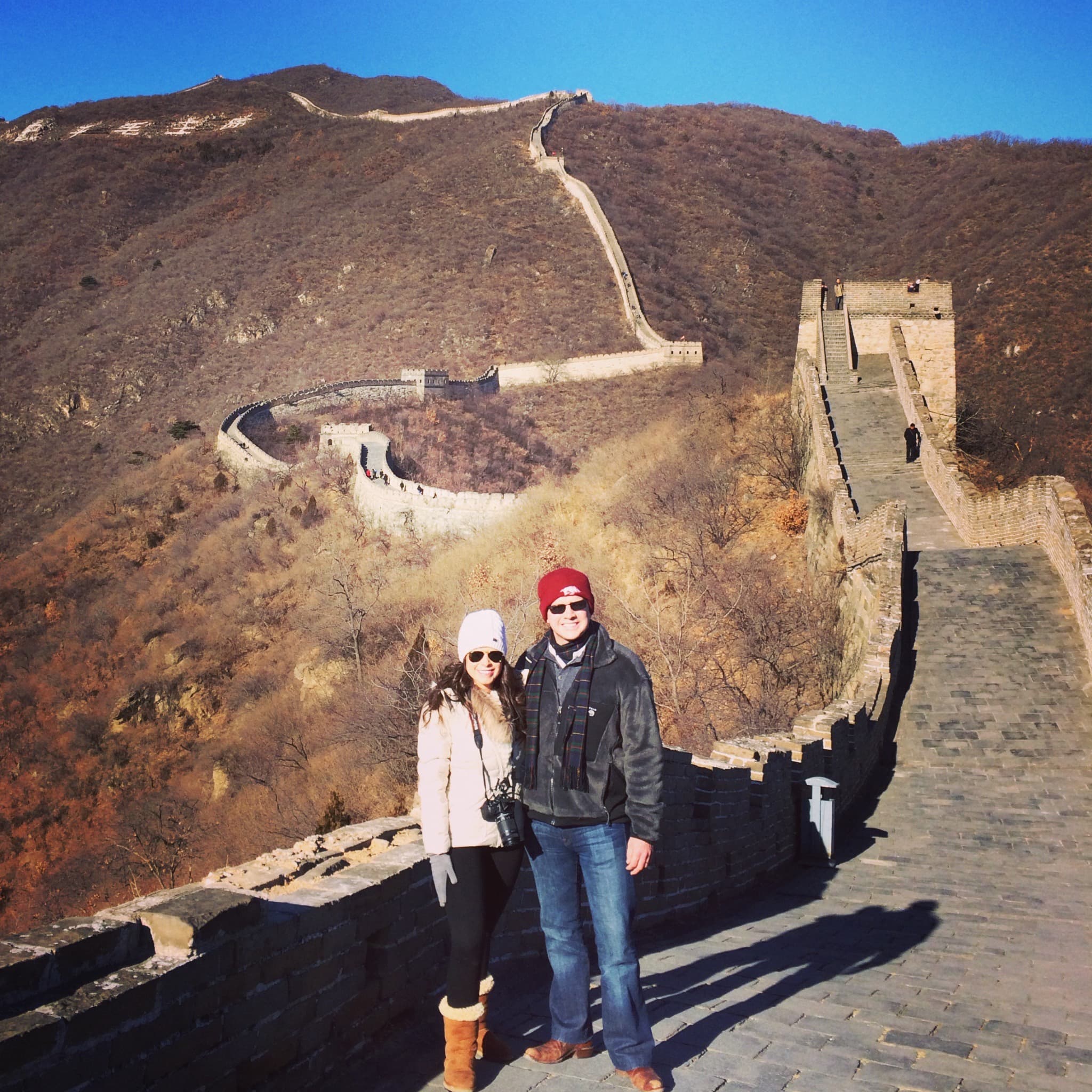 Advisor and partner posing side by side on the Great Wall of China under clear skies