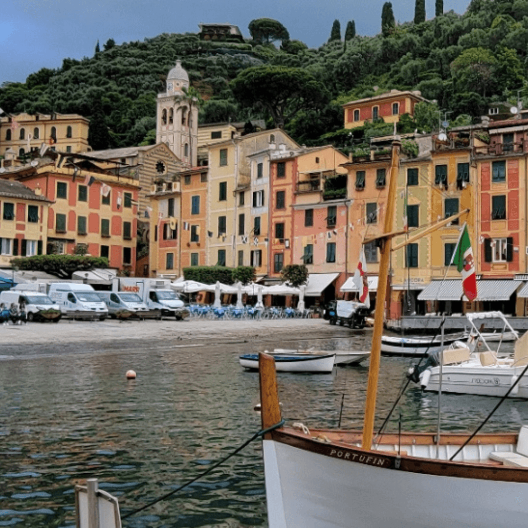 Pastel-colored buildings along the sea with boats docked offshore