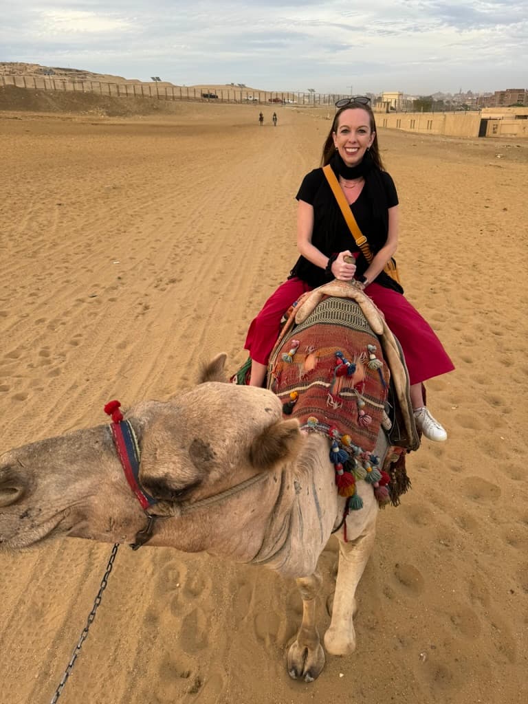 Advisor riding a camel through the desert on a cloudy day