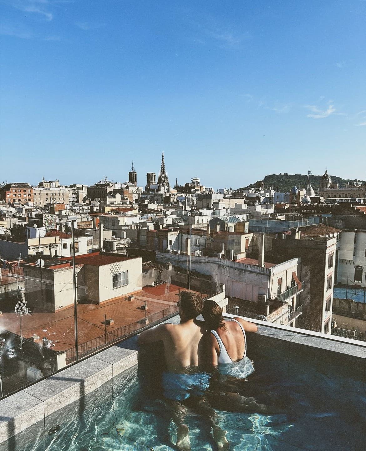 Advisor and partner in a rooftop infinity pool overlooking the cityscape on a sunny day
