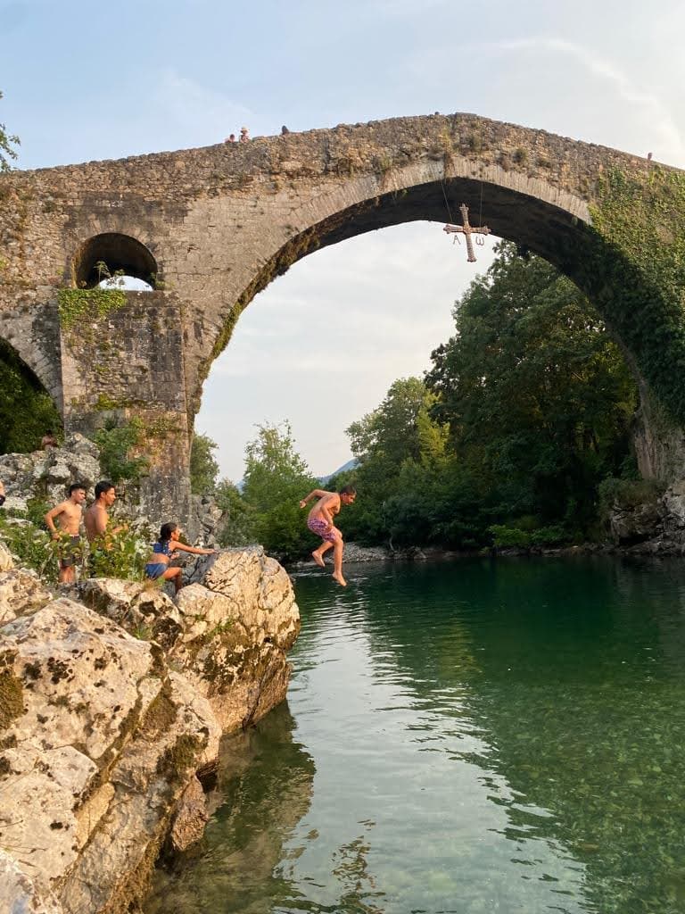 A view of a river and a large bridge with a group of people enjoying the water. 
