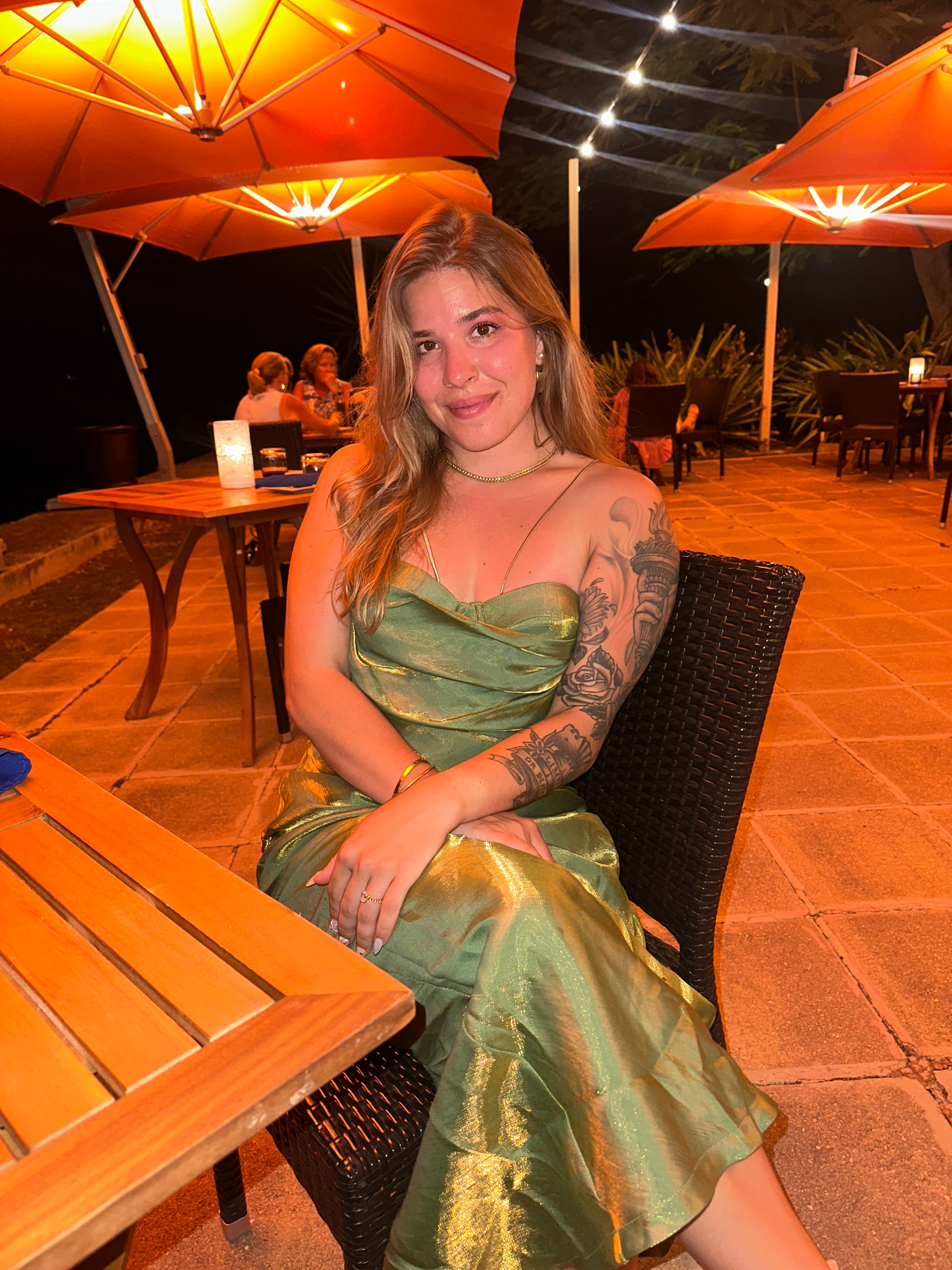 Advisor in a long green dressing sitting outdoors on a patio at night